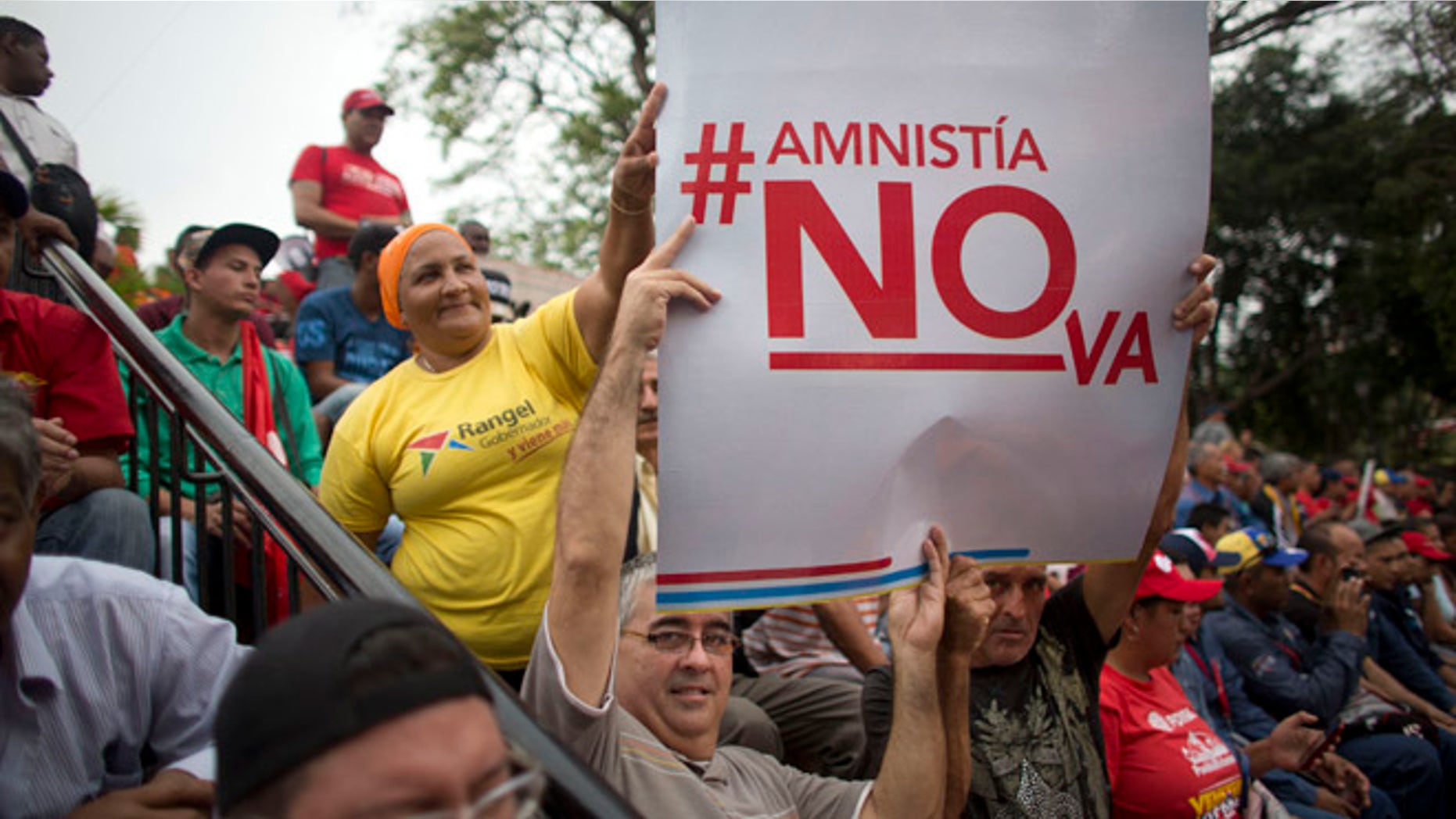 Supporters of President Nicolas Maduro hold a sign that reads in Spanish "Amnesty will not go" during a march, at Miraflores Presidential Palace in Caracas, Venezuela, Thursday, April 7, 2016. Groups allied to Venezuela's socialist administration marched to protest an amnesty law passed by the opposition controlled congress calling for release of those it deems to be political detainees. (AP Photo/Ariana Cubillos)