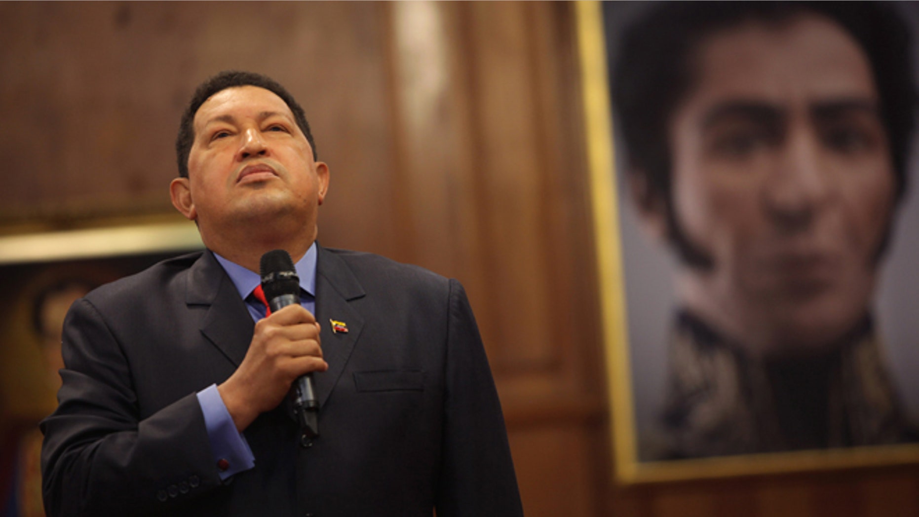 Backdropped by a portrait of independence hero Simon Bolivar, Venezuela's President Hugo Chavez talks during a press conference at the Miraflores palace in Caracas, Venezuela, Tuesday, Oct. 9, 2012. The 58-year-old former military officer Chavez won his fourth consecutive presidential bid Sunday and shows no signs of ballot fatigue. (AP Photo/Rodrigo Abd)