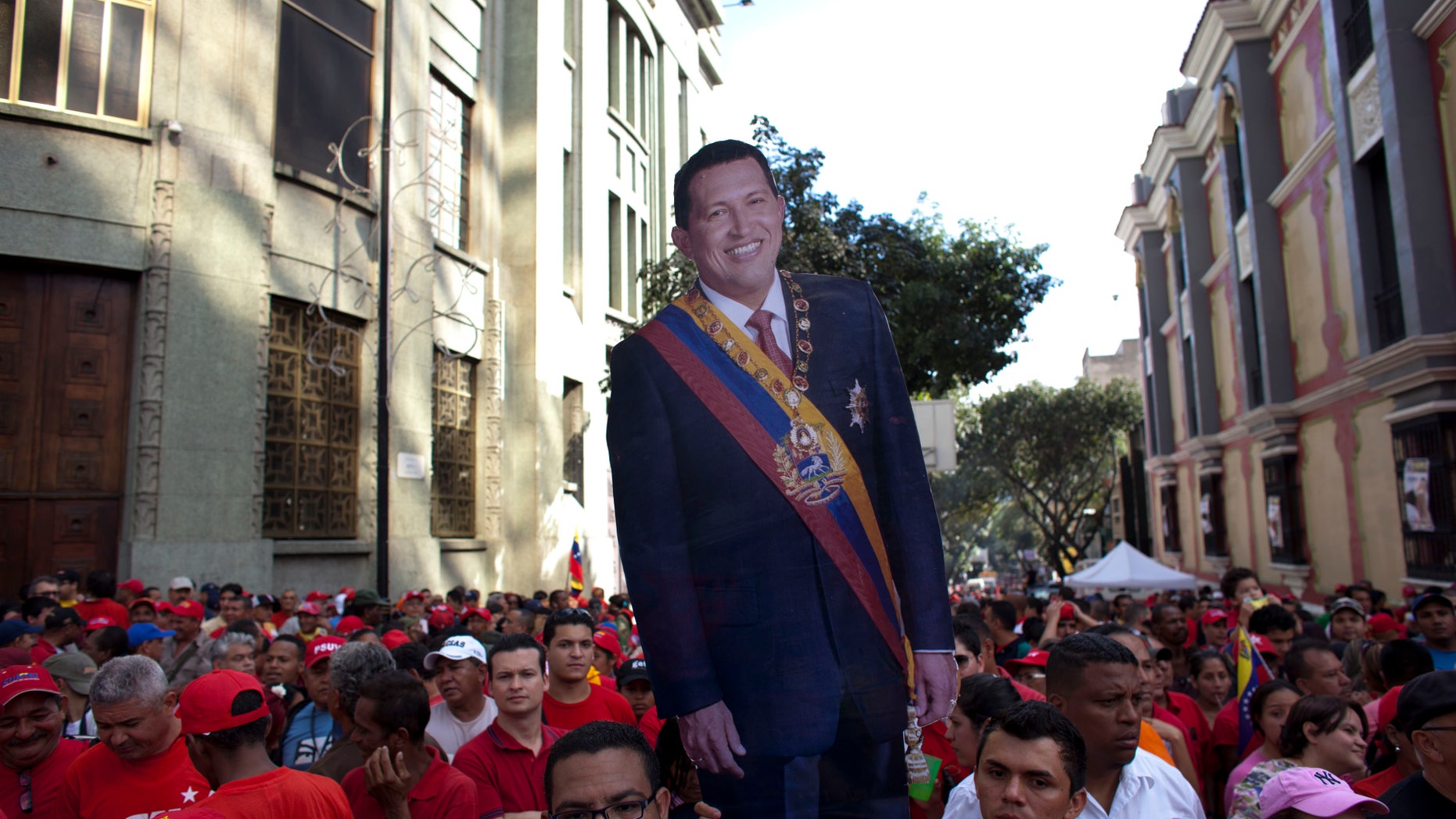 A life-size cut out image of Venezuela's President Hugo Chavez is carried by a Chavez supporter during a symbolic inauguration ceremony for Chavez in Caracas, Venezuela, Thursday, Jan. 10, 2013. The government organized the unusual show of support for the cancer-stricken leader on the streets outside Miraflores Palace on what was supposed to be Chavez's inauguration day. The Venezuelan leader, normally at the center of national attention, is so ill following a fourth cancer surgery in Cuba that he has made no broadcast statement in more than a month, and has not appeared in a single photo. Officials have not specified what sort of cancer he suffers or which hospital is treating him. (AP Photo/Ariana Cubillos)