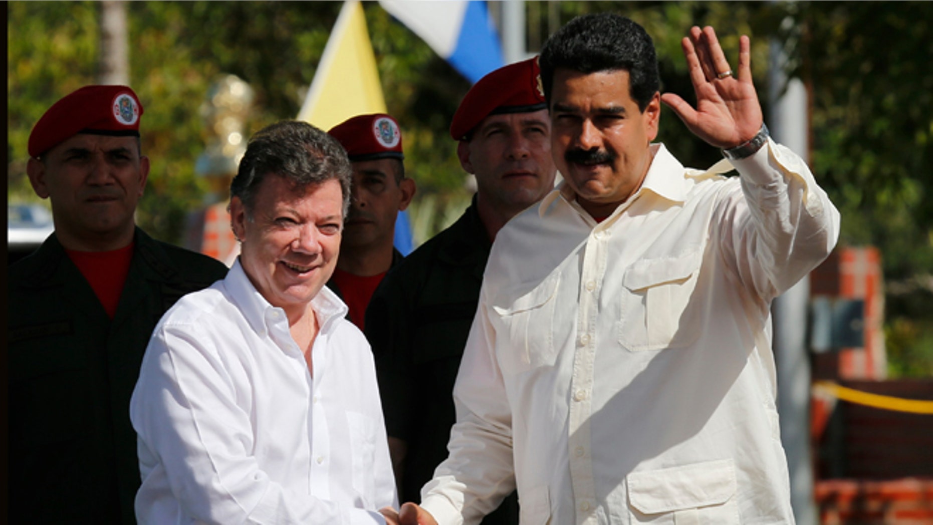 Venezuela's President Nicolas Maduro, right, waves as he shakes hands with Colombia's President Juan Manuel Santos prior a meeting in Puerto Ayacucho, Venezuela, Monday, July 22, 2013. (AP Photo/Fernando Llano)