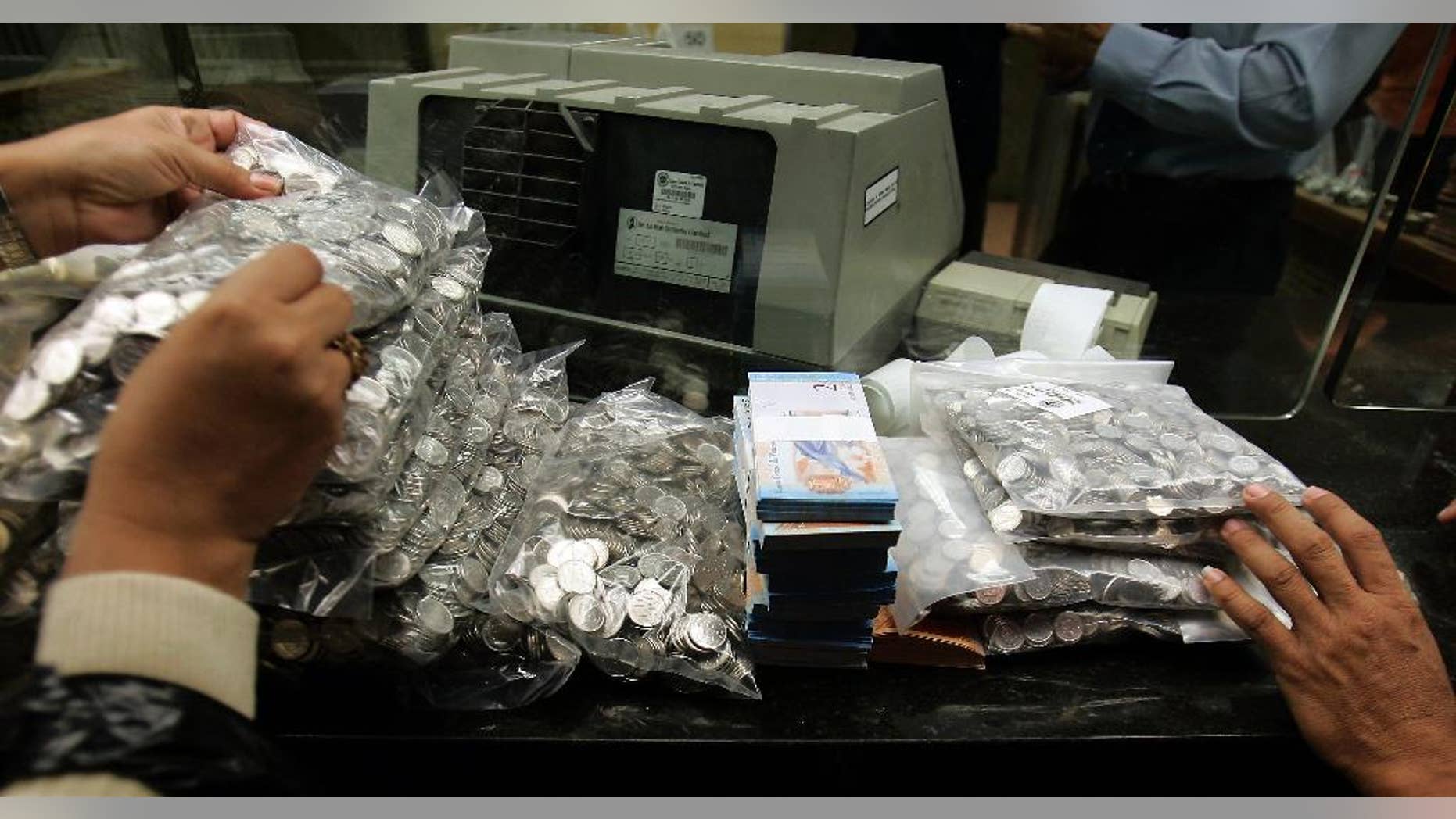 FILE - This Jan. 4, 2008 file photo shows bank workers handling Venezuela's currency, the "Bolivar Fuerte," or Strong Bolivar, at the Central Bank in Caracas, Venezuela. Venezuelans are expressing disbelief as the country’s currency has lost a quarter of its value on the black market in the space of a week in 2015, between May 14 and 22. (AP Photo/Fernando Llano, File)