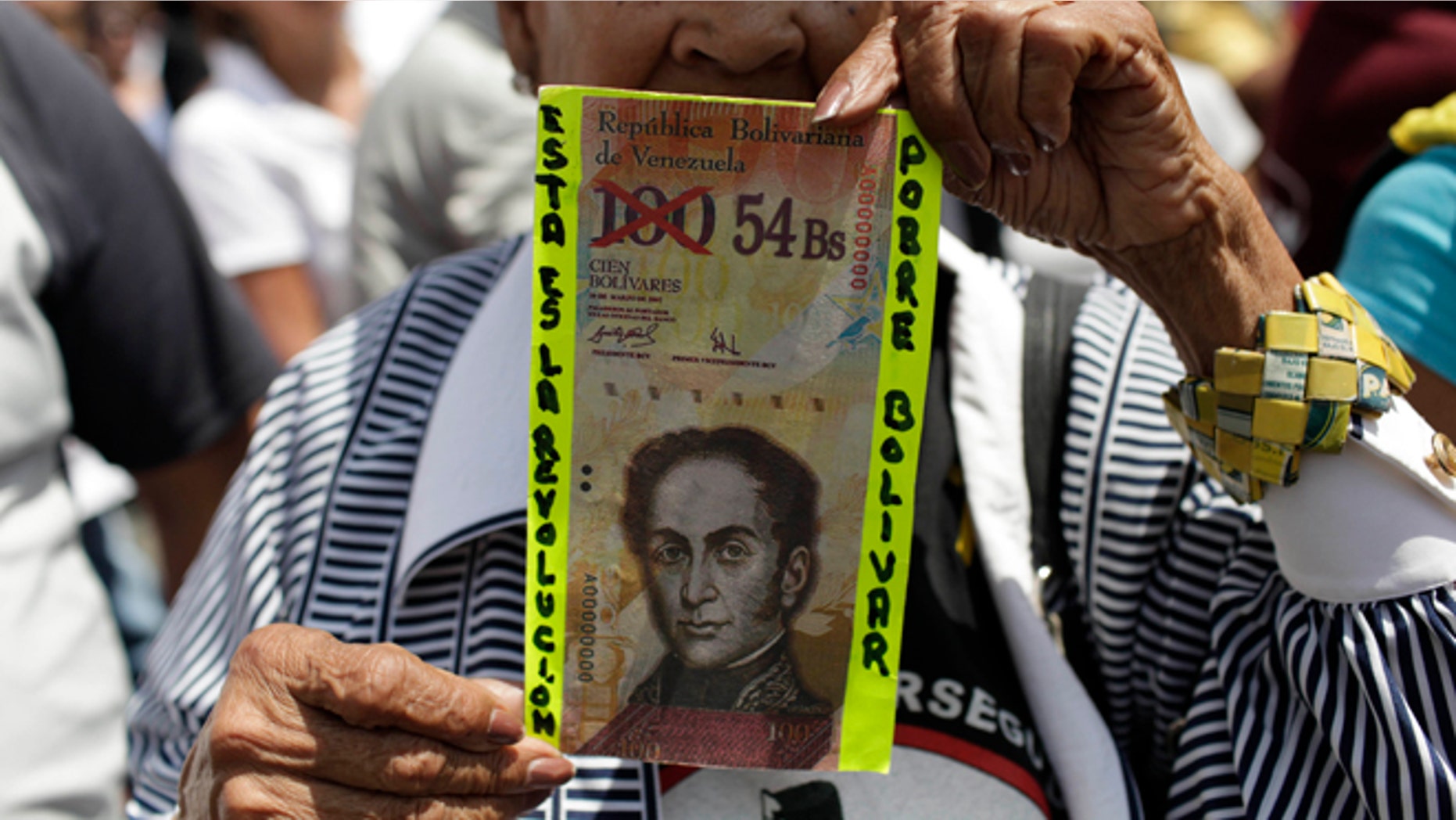 An anti-government protester holds up a fake Venezuelan banknote that reads in Spanish, "This is the revolution. Poor Bolivar."