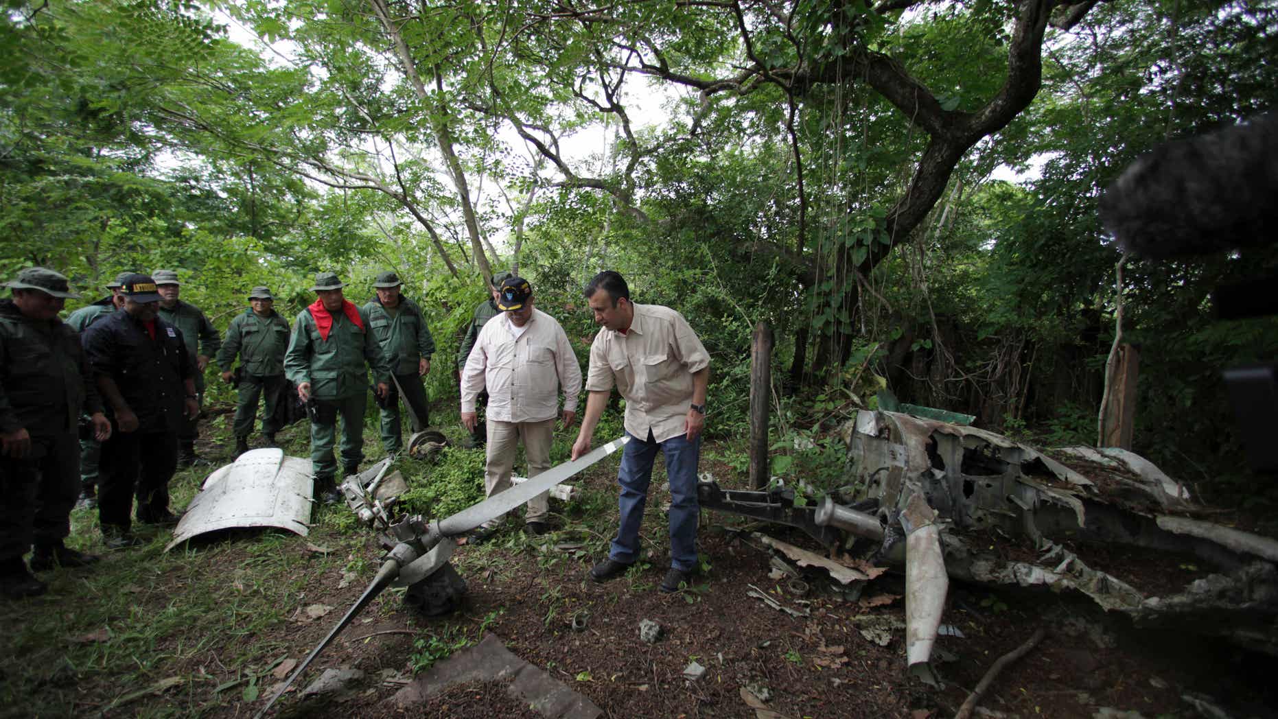 May 31, 2012: Venezuela's Justice Minister Tareck El Aissamiin, right, checks the remains of a plane used by drug traffickers during a military operation to destroy a clandestine airstrip used by drug traffickers near the border with Colombia in Riecito, Venezuela.