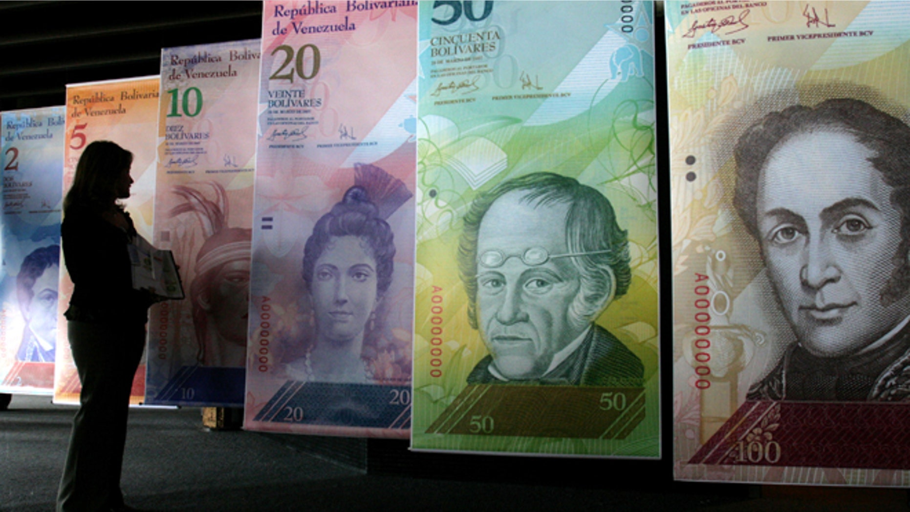 FILE - In this Oct. 24, 2007 file photo, a woman looks at oversized versions of the new Venezuelan currency, coined the 'Strong Bolivar' in Caracas, Venezuela. Venezuela's government announced Friday, Feb. 8, 2013, that it is devaluing the country's currency, a long-anticipated change expected to push up prices in the heavily import-reliant economy. Officials said the fixed exchange rate is changing from 4.30 bolivars to the dollar to 6.30 bolivars to the dollar. Venezuela's government has had strict currency exchange controls since 2003 and maintains a fixed, government-set exchange rate. (AP Photo/Howard Yanes, File)