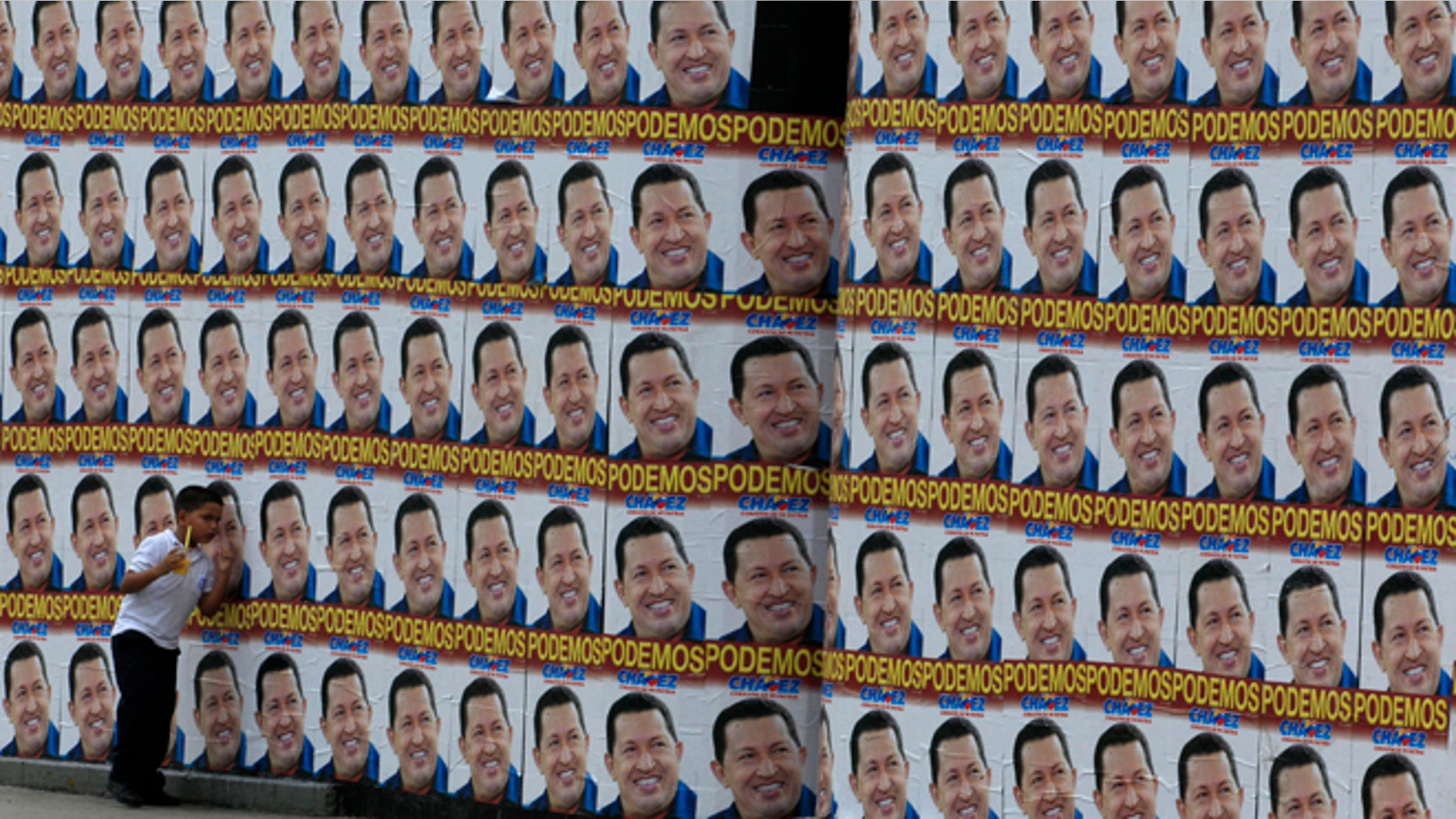 A boy walks beside a a wall covered with campaign posters of Venezuela's President Hugo Chavez in Caracas, Venezuela, Tuesday, Sept. 25, 2012. Chavez held a 10-point lead over rival Henrique Capriles in a polling company's final survey ahead of the Oct. 7 election, but the report released Tuesday showed Capriles narrowing the gap. (AP Photo/Fernando Llano)