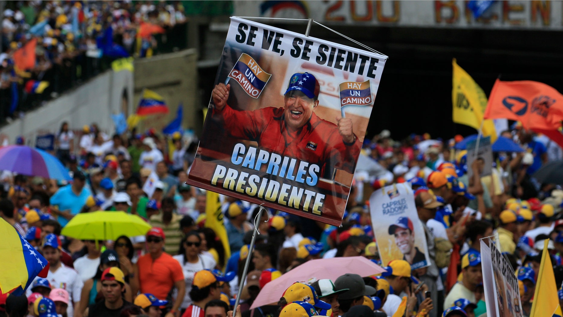 A supporter of opposition presidential candidate Henrique Capriles holds a poster that shows Venezuela's President Hugo Chavez as a supporter of Capriles during a campaign rally in Caracas, Venezuela, Sunday, Sept. 30, 2012. Capriles is running against Chavez in the country's Oct. 7 election. (AP Photo/Fernando Llano)
