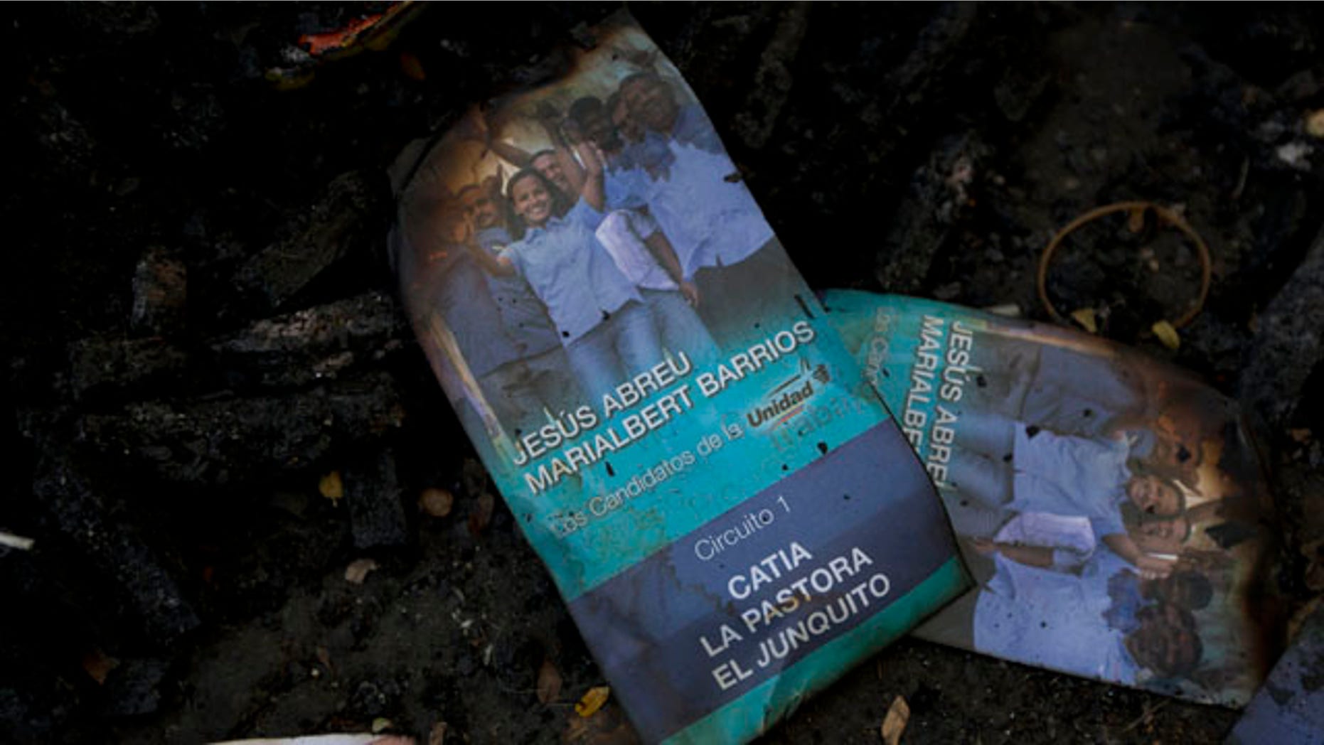 Nov. 24, 2015: Singed flyers promoting opposition congressional candidate Marialbert Barrios is seen on top of a trash pile at the Catia neighborhood, in Caracas, Venezuela. Remains of burned flyers and posters of opposition congressional candidates show traces of a battle that was fought in a busy street in the populous neighborhood Tuesday, after a group of alleged government supporters, some armed and on motorbikes, arrived and violently attacked supporters of the opposition as they hung election posters and flyers promoting their candidates. (AP Photo/Ariana Cubillos)