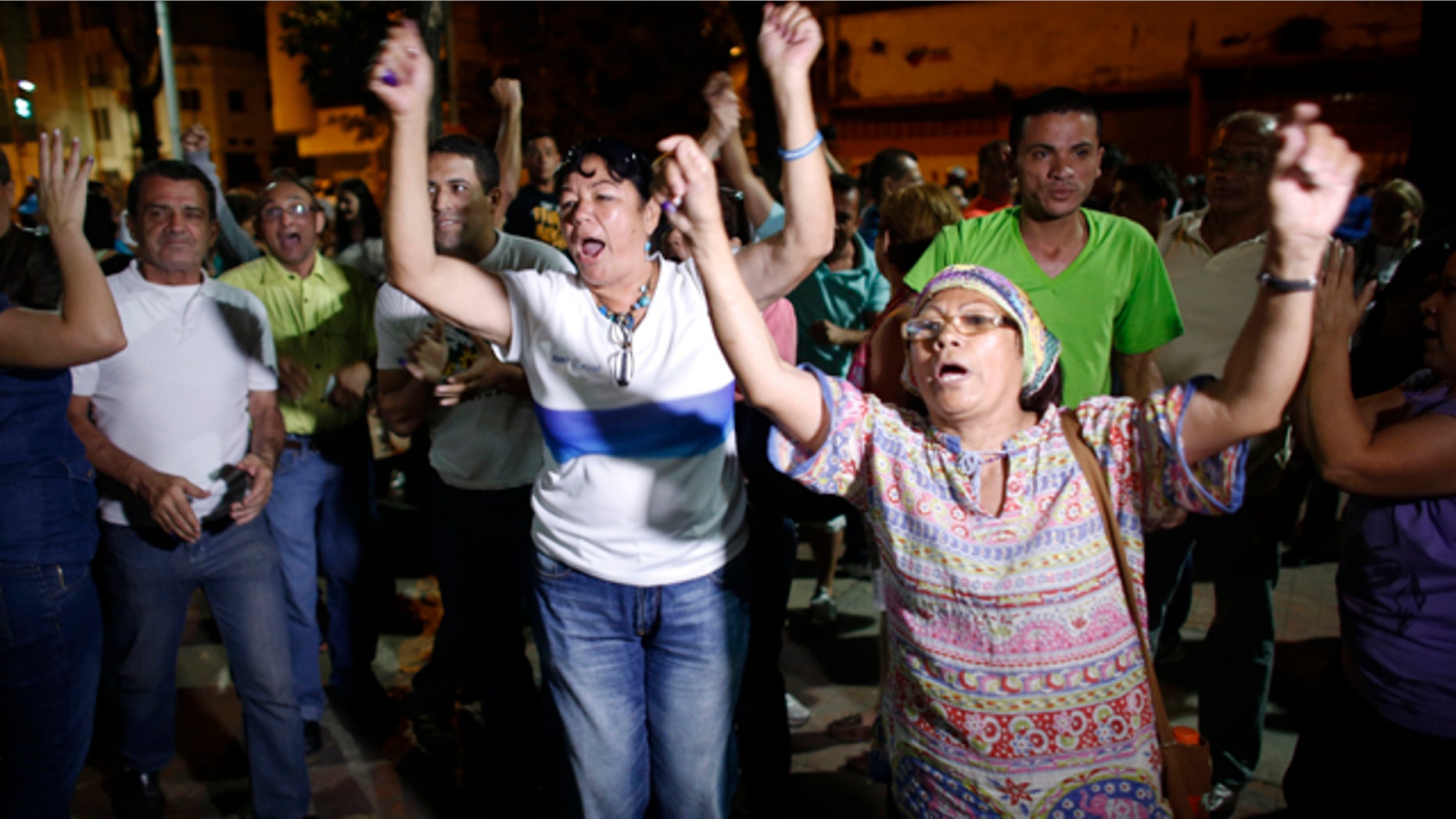 Dec. 6, 2015: Opposition supporters celebrates the closing of a polling station during congressional elections in Caracas, Venezuela. Some members of the opposition are angry after elections officials ordered polling centers to stay open for an extra hour, even if no one was standing in line to vote. Government opponents mobbed some voting stations demanding that the National Guard stick to the original schedule of closing at 6 p.m. (AP Photo/Ariana Cubillos)
