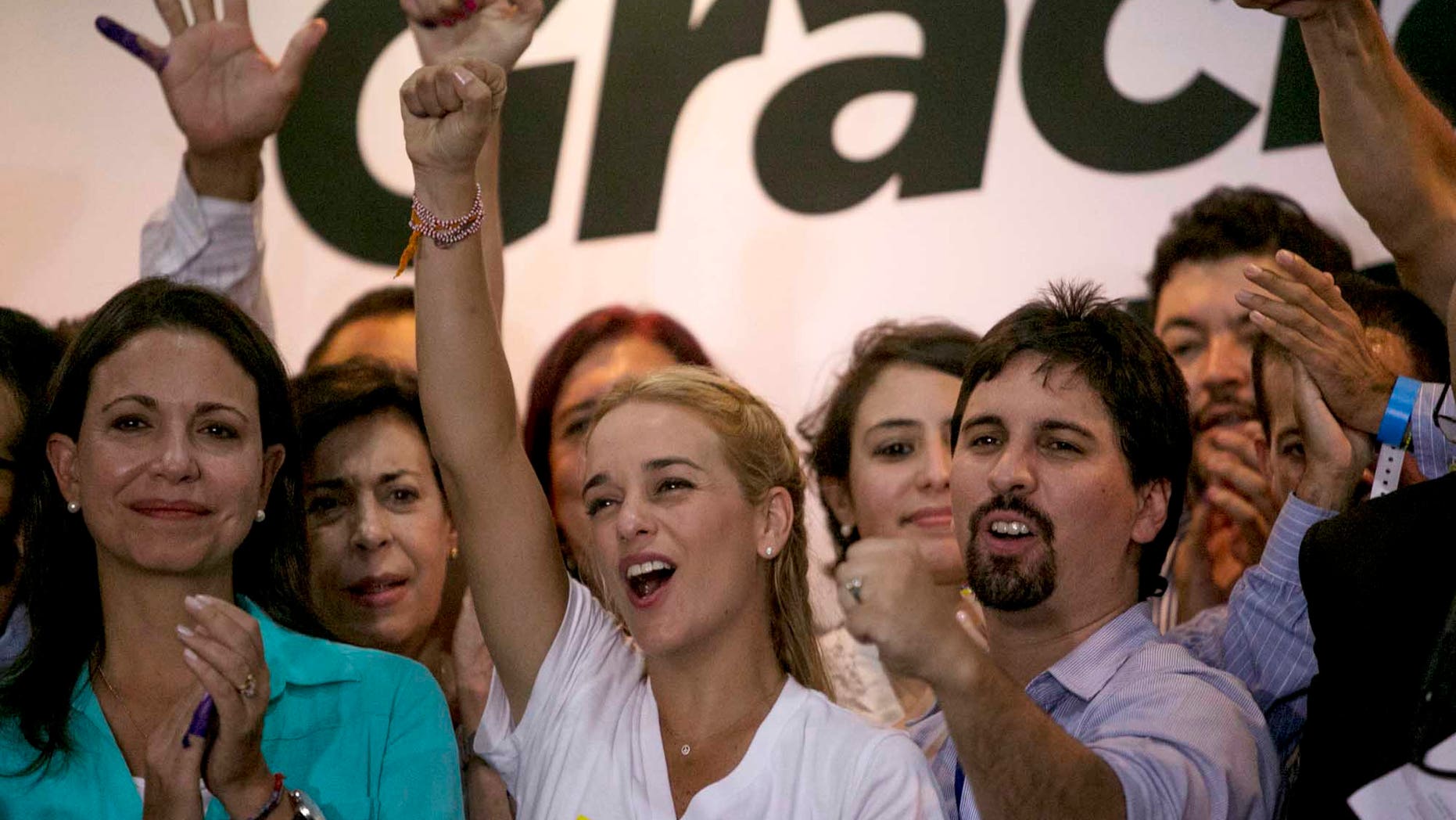 Lilian Tintori wife of jailed Venezuelan opposition leader Leopoldo Lopez, center, Freddy Guevara, of the Voluntad Popular party, right, and former opposition congresswoman Maria Corina Machado, left, celebrate in Caracas, Venezuela, early Monday, Dec. 7, 2015. Venezuela's opposition won control of the National Assembly by a landslide on Sunday, delivering a major setback to the ruling party and altering the balance of power after 17 years of socialist rule.(AP Photo/ Alejandro Cegarra)