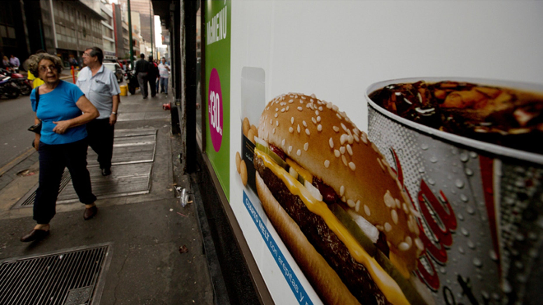A customer glances at a McDonalds' banner menu showing a burger accompanied by arepas or corn cakes, instead of fries, in Caracas, Venezuela, Tuesday, Jan. 6, 2015. McDonalds franchises in Venezuela have run out of potatoes and are now serving South American alternatives like deep-fried arepas or yuca, a starchy tuberous root. The franchisers are blaming a contract dispute with West Coast dock workers for halting the export of frozen fries to the country. (AP Photo/Fernando Llano)