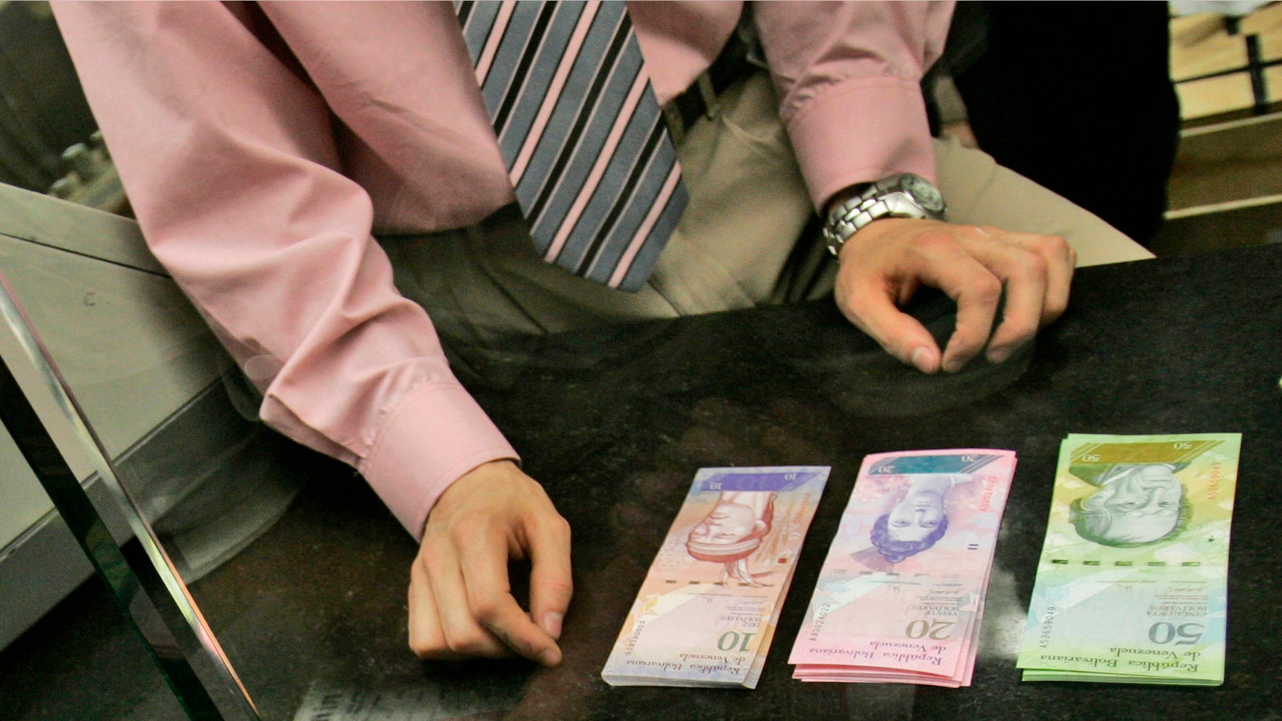 A bank worker changes old Bolivares for Venezuela's new currency in Caracas, Venezuela.