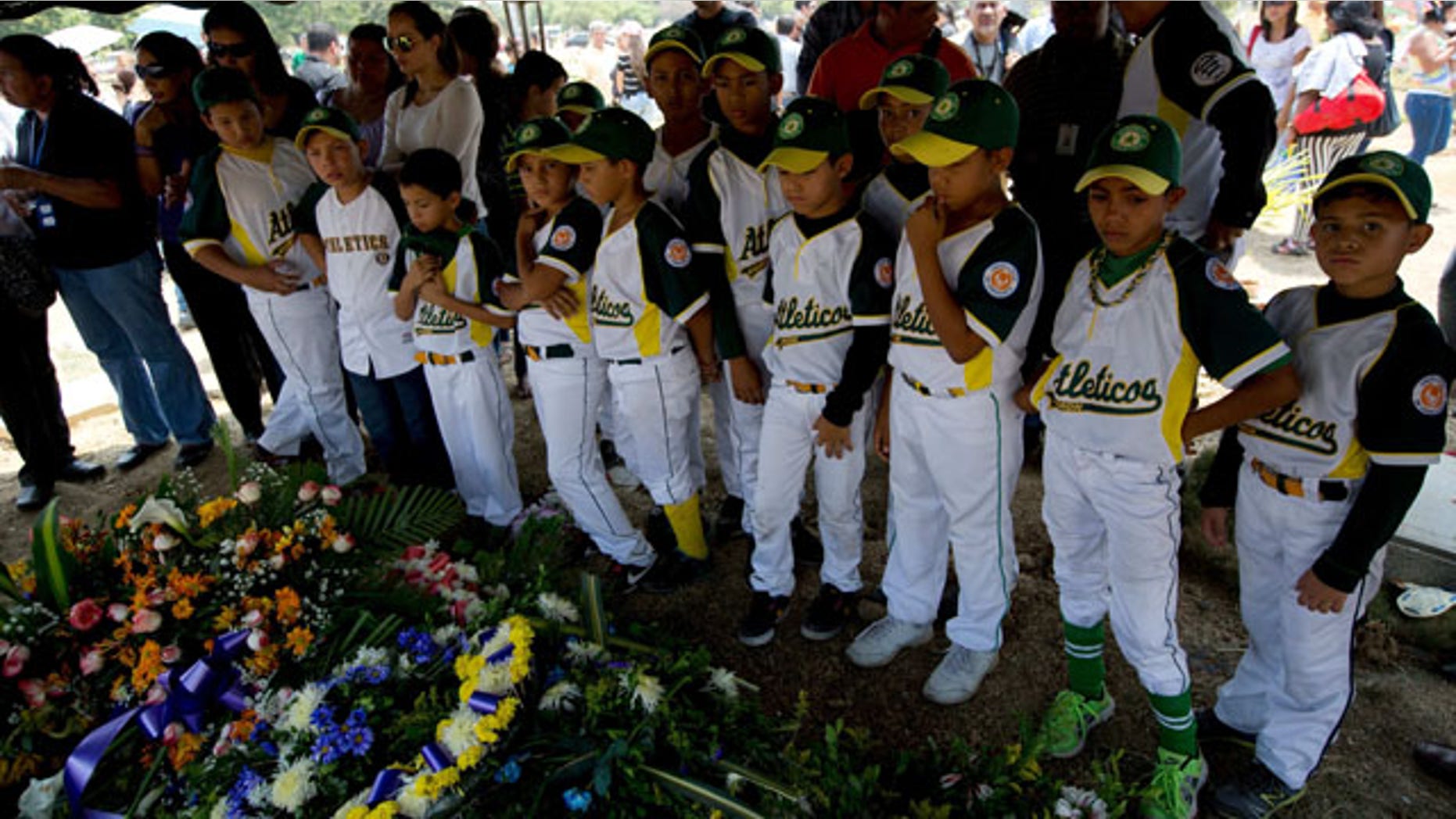 March 14, 2014: Boys that play in a minor league baseball team "Atleticos de Crimon" mourn their coach, Guillermo Sanchez after his funeral grave in in Valencia, Venezuela. The people of the poor district of La Isabelica were made to pay for taking to the streets in anti-government protests. More than a dozen masked men on motorcycles roared through, shooting up a barricade and killing a university student and a 42-year-old man painting his house. (AP Photo/Fernando Llano)