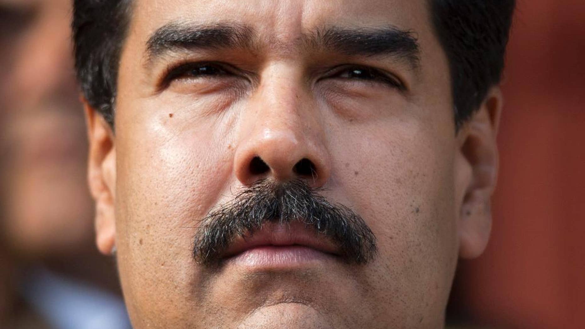 FILE - I this March 17, 2015, file photo, Venezuela's President Nicolas Maduro listens to the playing of national hymns as he welcomes regional leaders to Miraflores presidential palace for an emergency ALBA meeting in Caracas, Venezuela. On Thursday, Oct. 5, 2015, Maduro repeated a promise to shave off his trademark moustache if his government doesn’t meet a year-end goal of handing over its 1 millionth public housing unit to a family. (AP Photo/Ariana Cubillos, File)