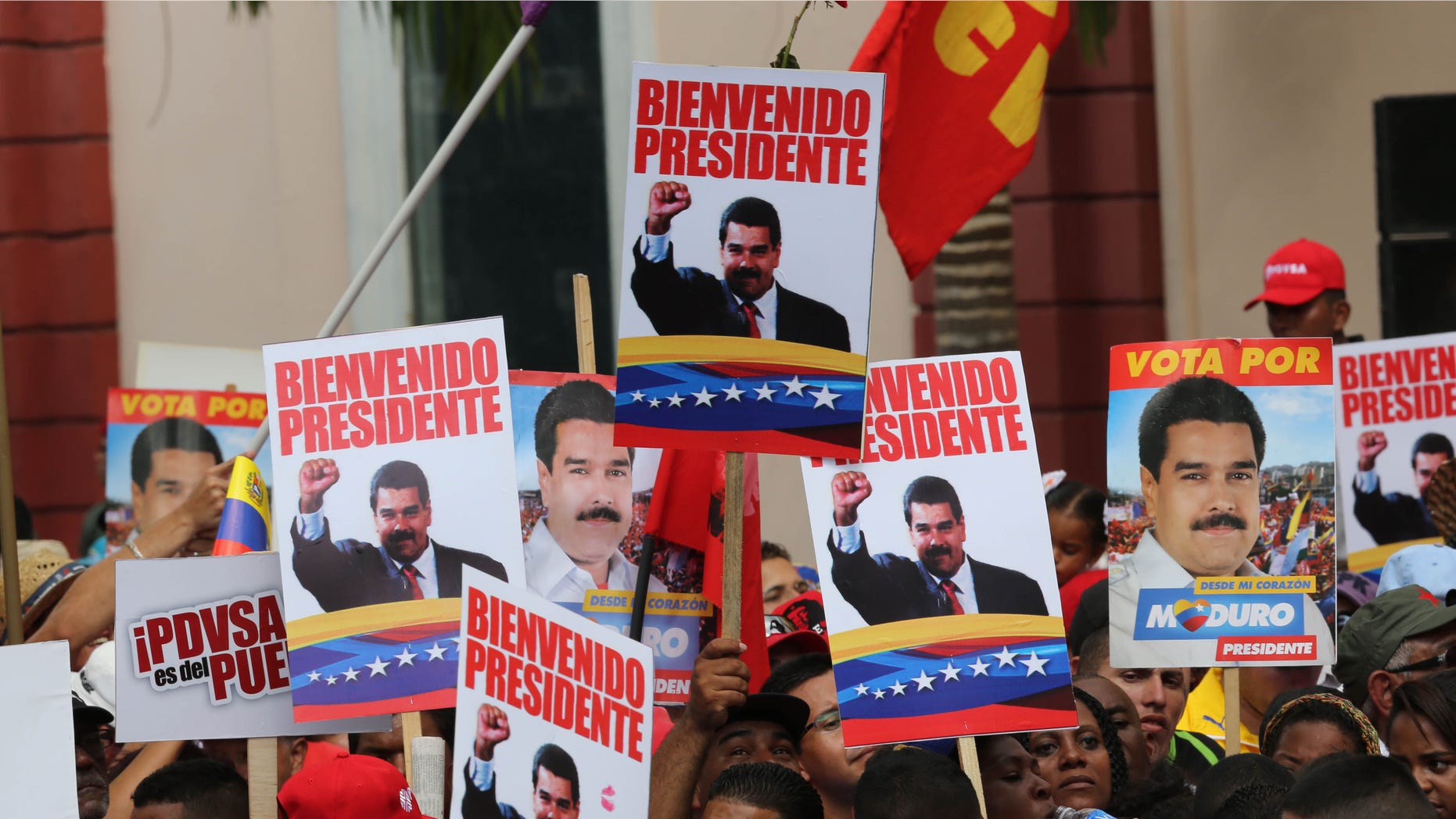 Supporters hold placards with images of Venezuela's President Nicolas Maduro and a message that reads in Spanish; "Welcome president,"at the Miraflores Palace in Caracas, Venezuela, Saturday, Jan. 17, 2015, during a ceremony welcoming the leader back home. Maduro has been away visiting seven nations to seek loans and make a plea for lower oil production. The price of oil has crashed in recent months, driving Venezuelaâs oil-based economy to the brink. (AP Photo/Ariana Cubillos)