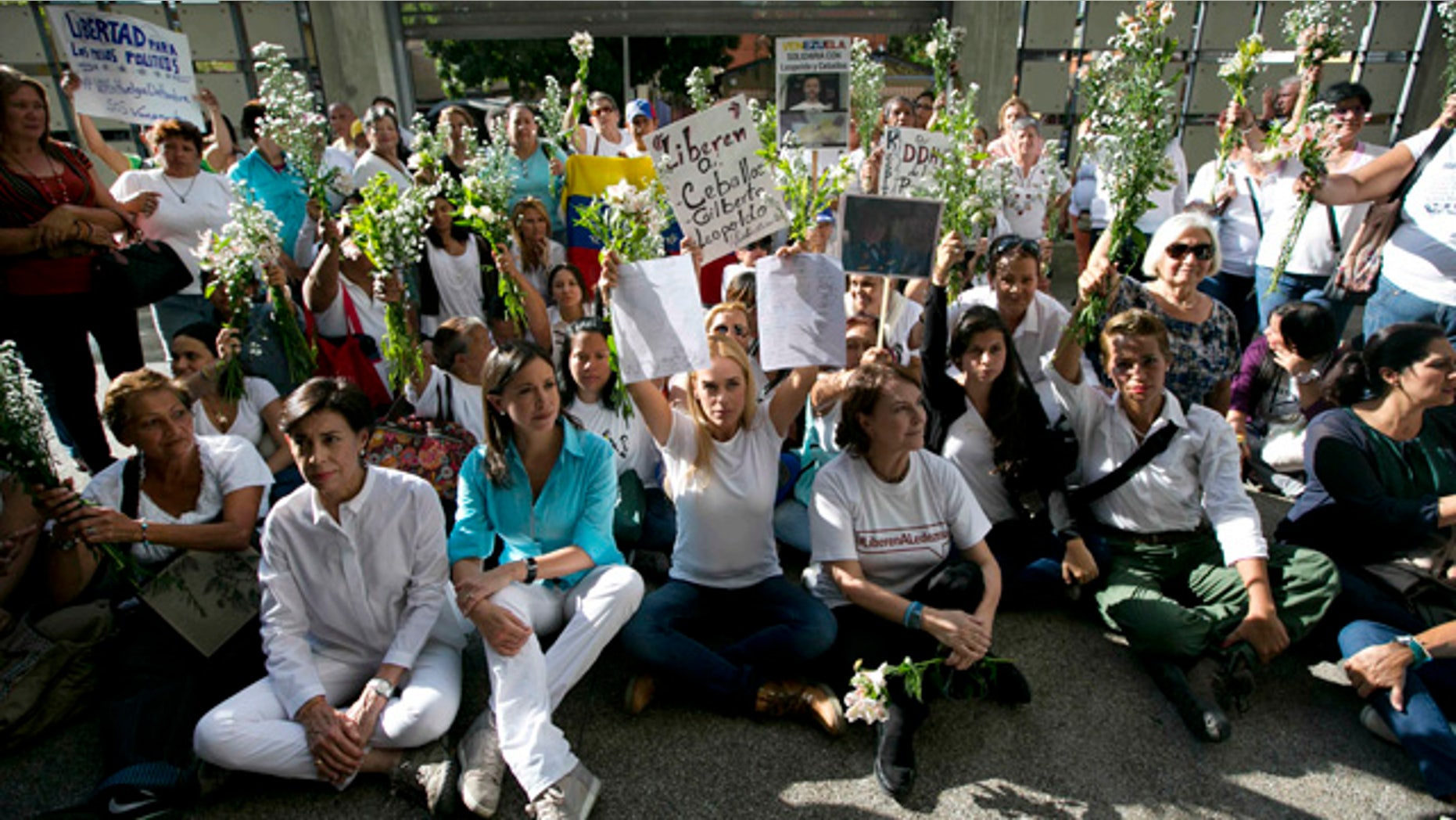 June 12, 2015: Flanked by Venezuela's former opposition lawmaker Maria Corina Machado, left center, and Mitzy Capriles de Ledezma, wife of imprisoned Caracas Mayor Antonio Ledezma, right center, Lilian Tintori, wife of jailed opposition leader Leopoldo Lopez, holds up a letter signed by supporters, during a demonstration at the entrance of the building where the Brazilian embassy operates in Caracas. (AP Photo/Ariana Cubillos)