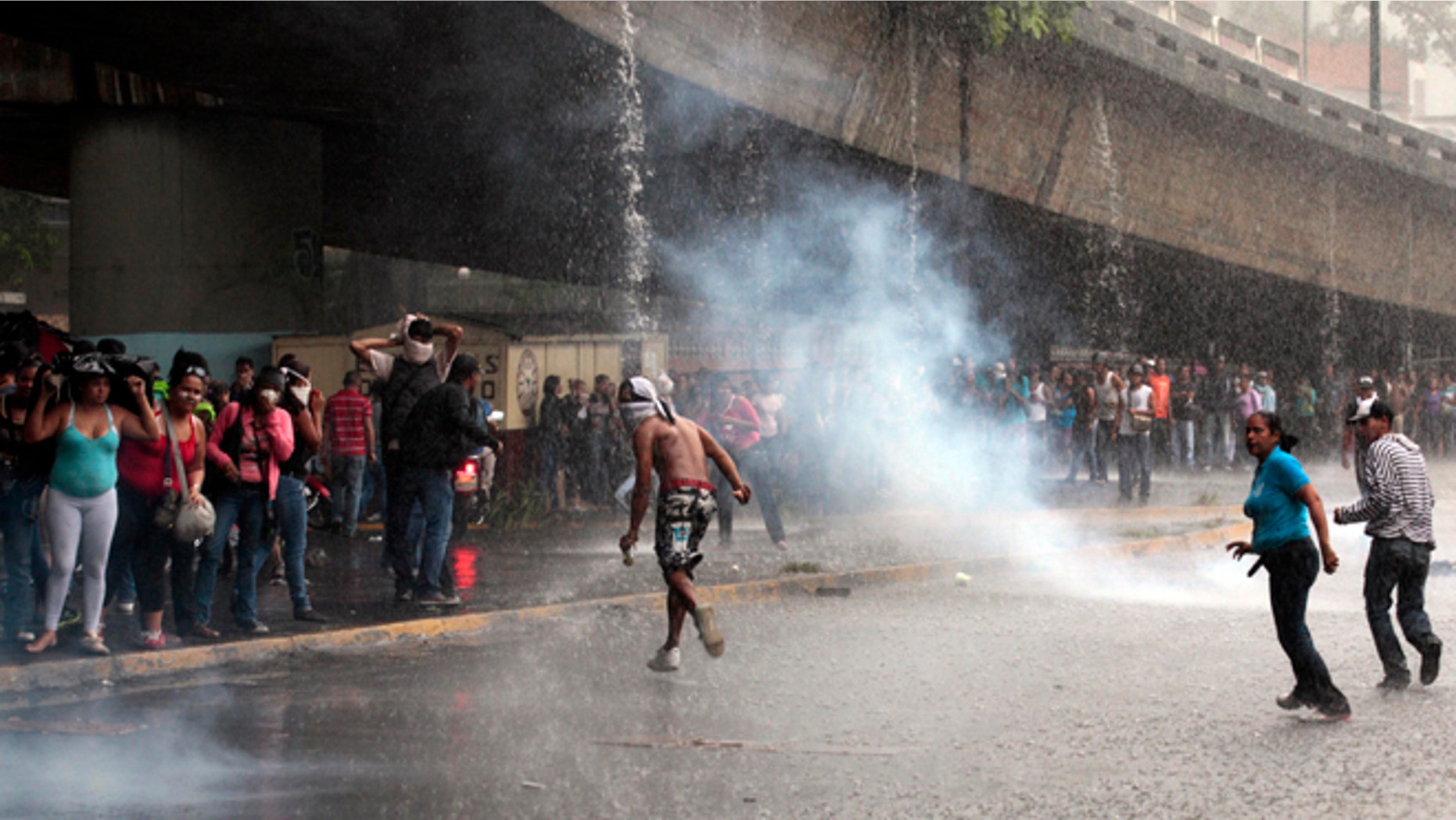 Mary 8, 2012: Relatives of inmates, protesting against measures taken by authorities to control a riot at the La Planta prison, run away from tear gas canisters fired by National Guard soldiers during clashes outside the prison in Caracas, Venezuela.