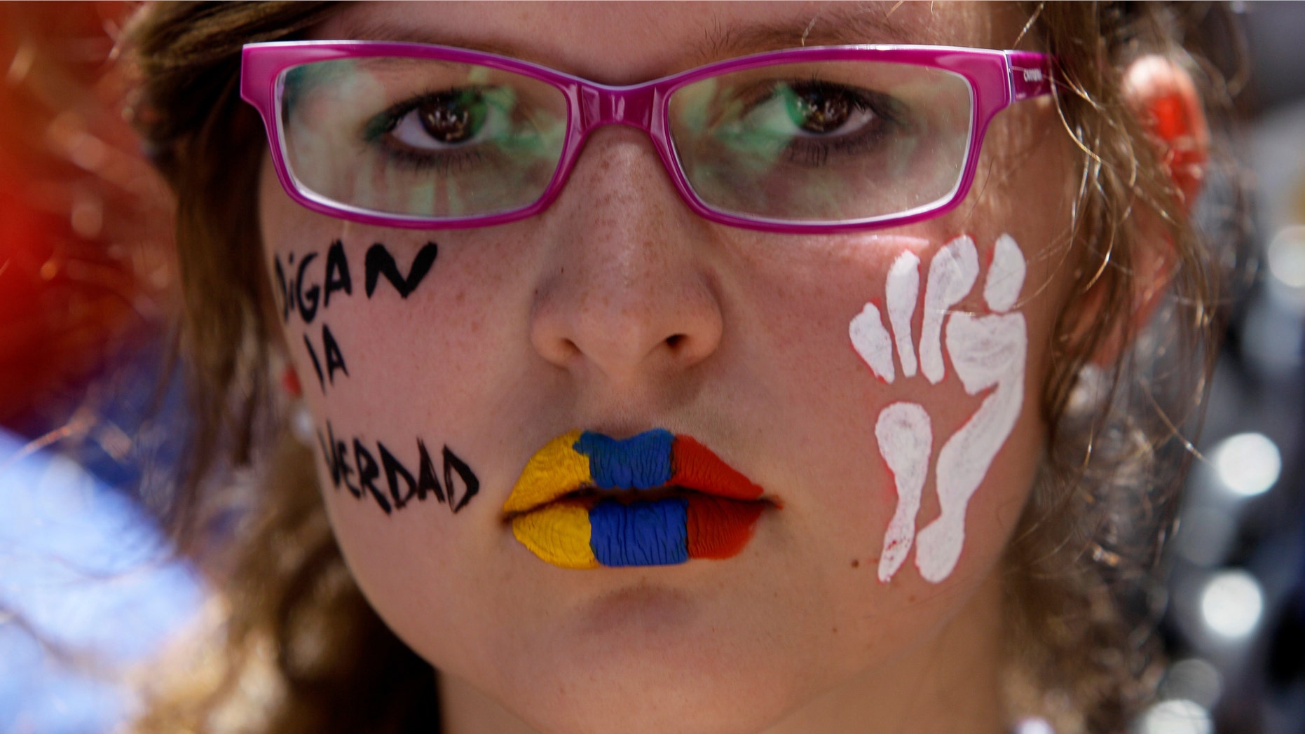 A demonstrator with her lips painted with the colors of the Venezuelan flag attends a protest in Caracas, Venezuela, Sunday, March 3, 2013. Hundreds of protesters took to the streets of Venezuela's capital on Sunday, demanding the government provide complete details about the health of ailing Venezuela's President Hugo Chavez. (AP Photo/Fernando Llano)
