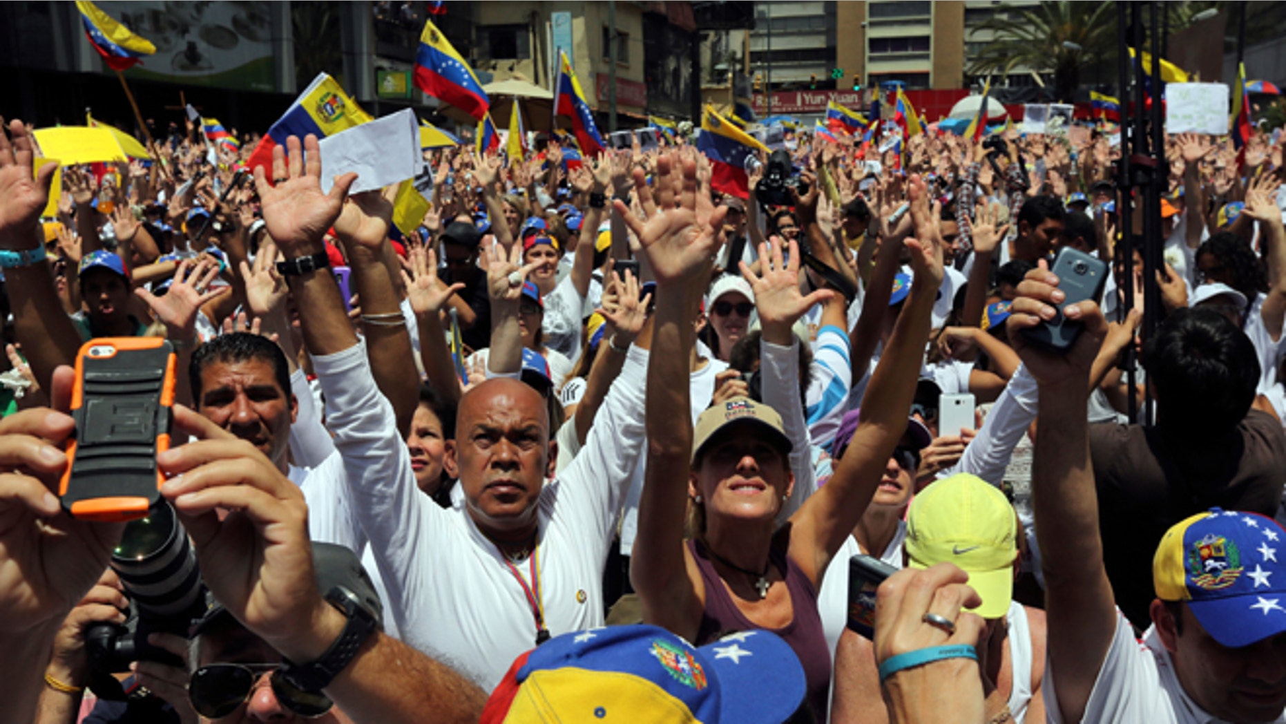 Demonstrators raise their arms in unison during a demonstration honoring the victims who died in last month's anti-government protests, in Caracas, Venezuela, Tuesday, March 4, 2014. Venezuelan opposition leader Henrique Capriles called Monday for citizens to begin organizing committees that could sustain the pressure that continuing street protests have placed on President Nicolas Maduro's government. (AP Photo/Fernando Llano)