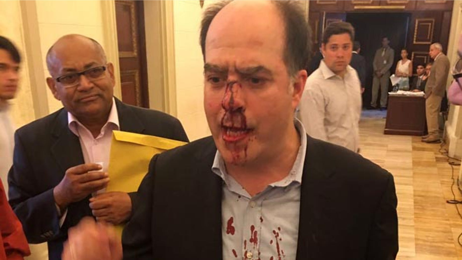 In this photo provided by Elyangelica Gonzalez, Venezuelan opposition Congressman Julio Borges arrives to the National Assembly after he was attacked by government supporters during a protest outside the National Electoral Council, CNE, in Caracas, Venezuela, Thursday, June 9, 2016. Opposition members were turned back from the headquarters of Venezuela's electoral body where the group attempted to enter to demand the government allow it to pursue a recall referendum against President Nicolas Maduro. (Elyangelica Gonzalez via AP)