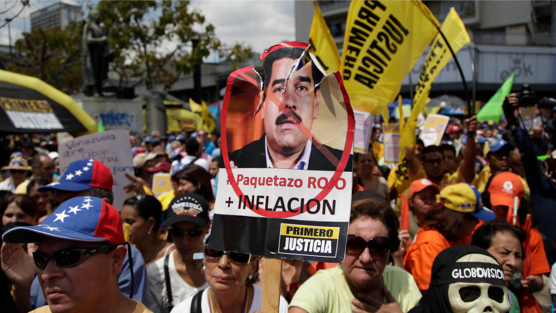 A protester holds up a picture of Venezuela's Vice President Nicolas Maduro that reads in Spanish "Big red package, plus inflation" during an opposition demonstration against of the devaluation of the currency in Caracas, Venezuela, Saturday, Feb. 23, 2013. (AP Photo/Ariana Cubillos)