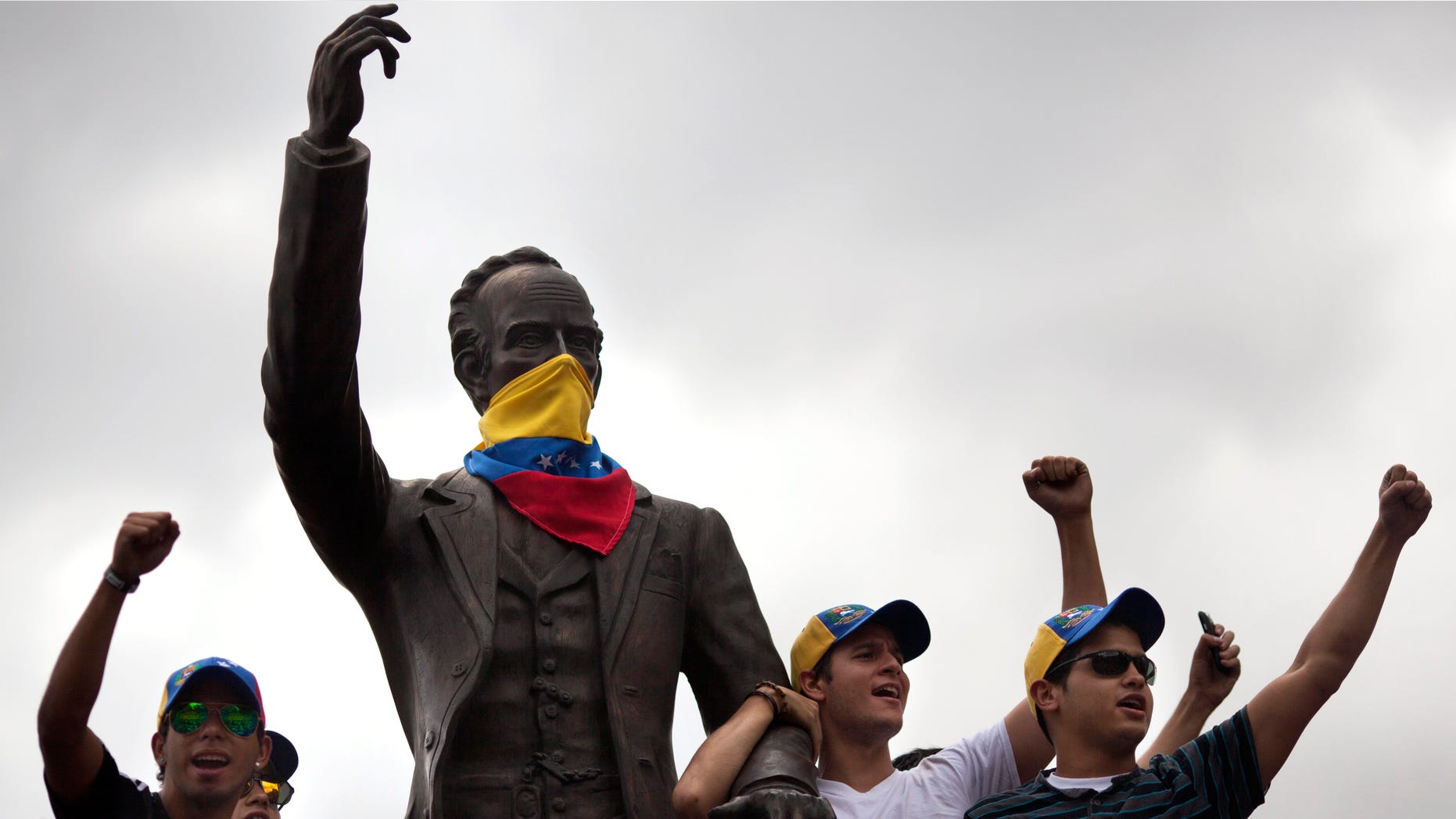 Demonstrators chant anti-government slogans next to a statue of Cuban writer and hero Jose Marti masked with a Venezuelan flag in Caracas, Venezuela, Sunday, March 2, 2014. Since mid-February, anti-government activists have been protesting high inflation, shortages of food stuffs and medicine, and violent crime in a nation with the world's largest proven oil reserves. (AP Photo/Rodrigo Abd)