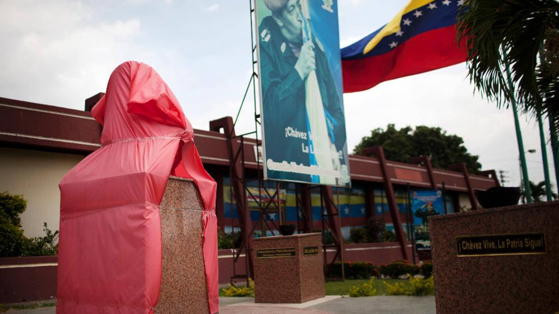 A new bust of former Venezuela's President Hugo Chavez is protected by a red fabric at a Bolivarian National Guard base in Valencia, Venezuela, Saturday, March 1, 2014. To mark Chavez’s passing, President Nicolas Maduro has decreed a 10 day-long commemoration - longer than the week-long period of official mourning that followed his death at the age of 58 on March 5, 2013. (AP Photo/Rodrigo Abd)