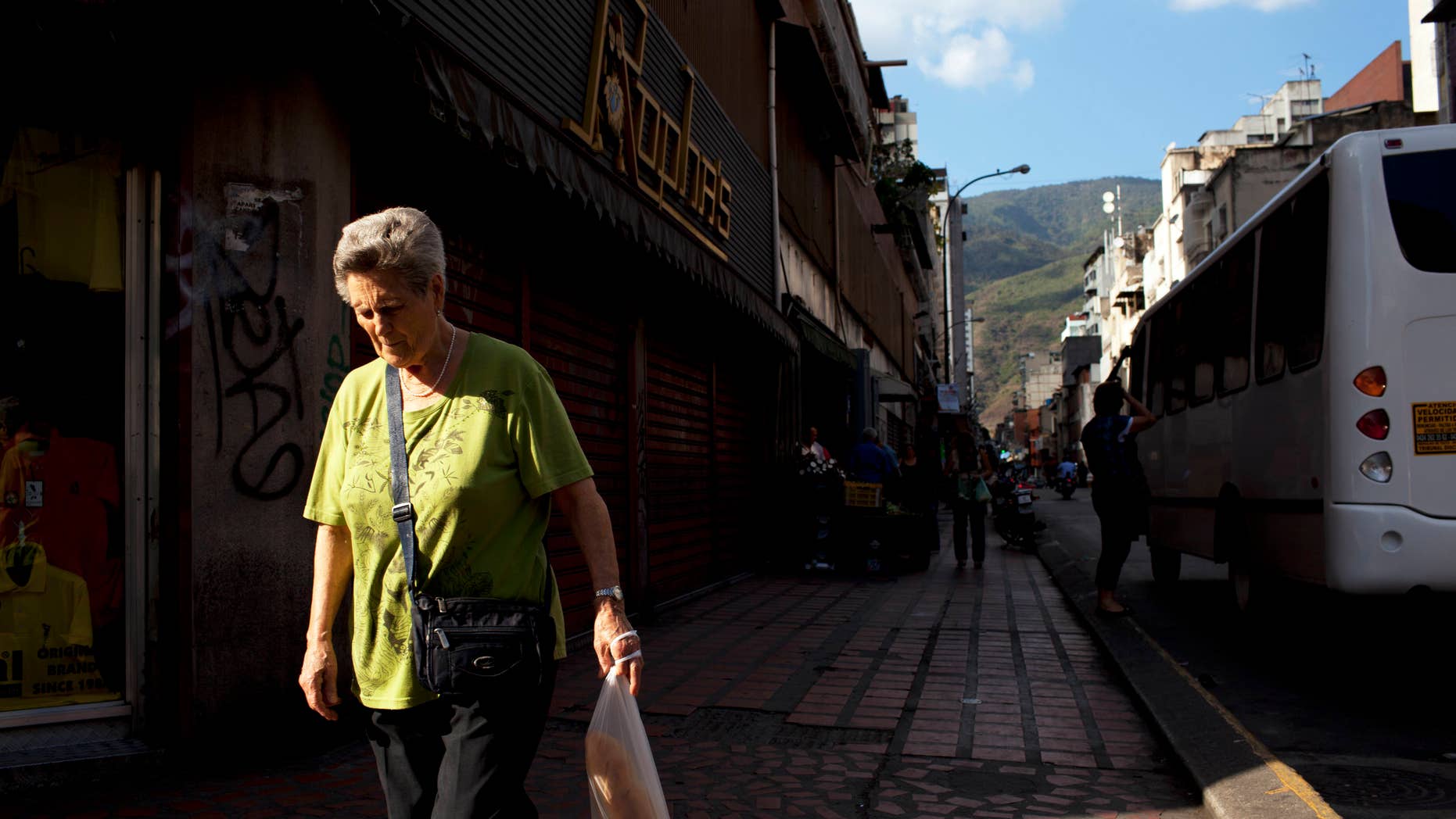 FILE - In this Feb. 20, 2014 file photo, a woman walks downtown after buying bread in Caracas, Venezuela. Venezuelans may soon have to scan their fingers to buy bread at the supermarket. President Nicolas Maduro announced late Wednesday, Aug. 20, 2014 a new, mandatory grocery fingerprinting system to combat food shortages. In the spring, Venezuela tried a similar system in government-run supermarkets on a voluntary basis. (AP Photo/Rodrigo Abd, File)