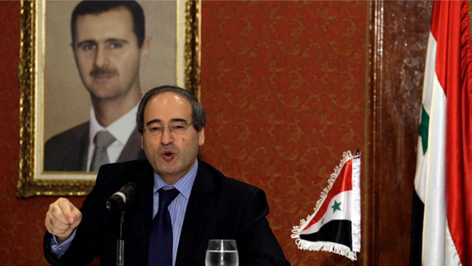 Backdropped by a framed picture of Syrian President Bashar al-Assad, Syria's Deputy Foreign Minister Faisal al-Mokdad speaks during a news conference at a local hotel in Caracas, Venezuela, Tuesday, Nov. 27, 2012. T(AP Photo/Fernando Llano)