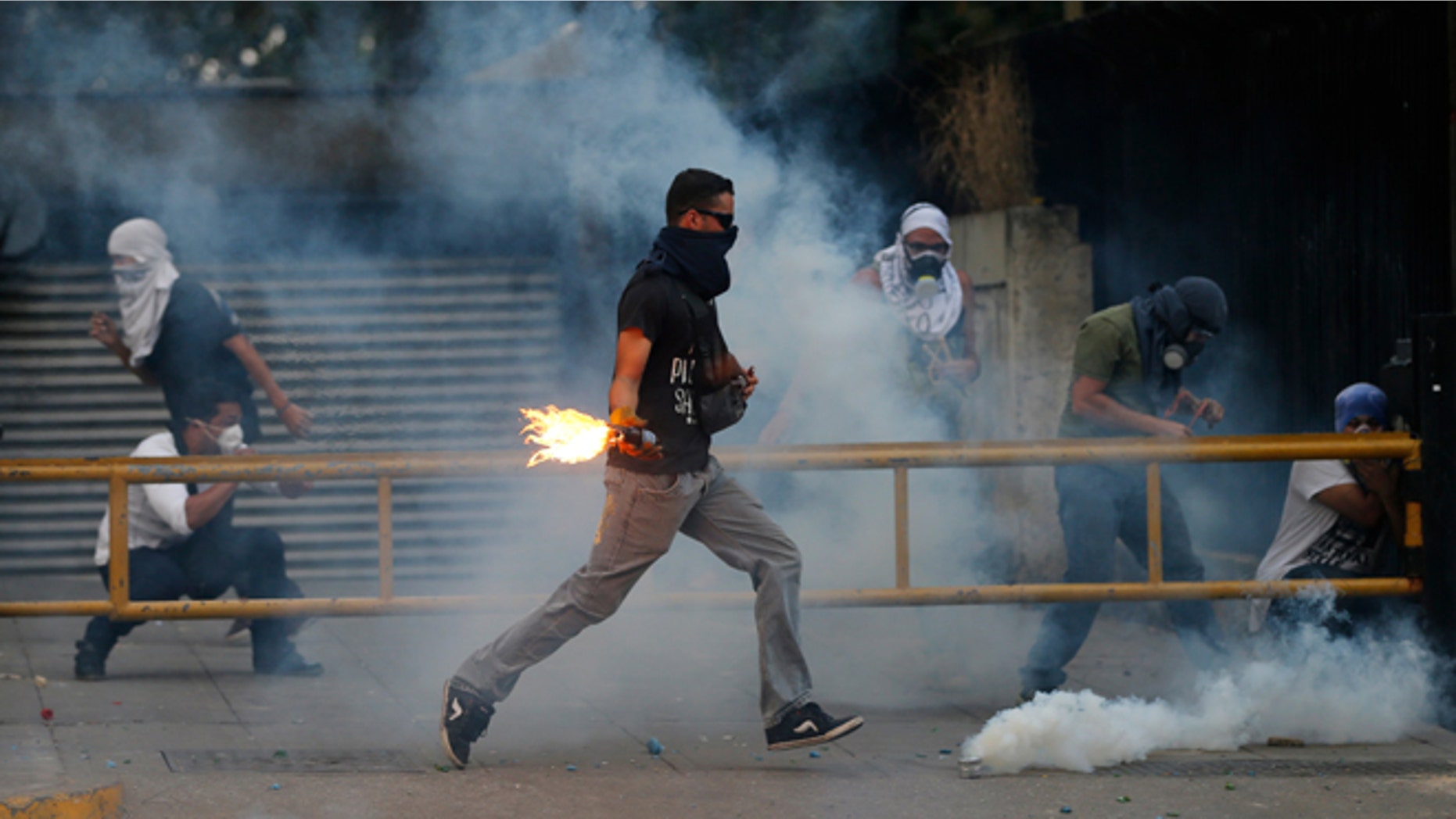 A demonstrator runs to throw a molotov bomb against Bolivarian National Police officers during clashes in Caracas, Venezuela, Thursday, March 6, 2014. A National Guardsman and a civilian were killed Thursday in a clash between residents of a Caracas neighborhood and armed men who tried to remove a barricade, Venezuelan officials said. (AP Photo/Fernando Llano)
