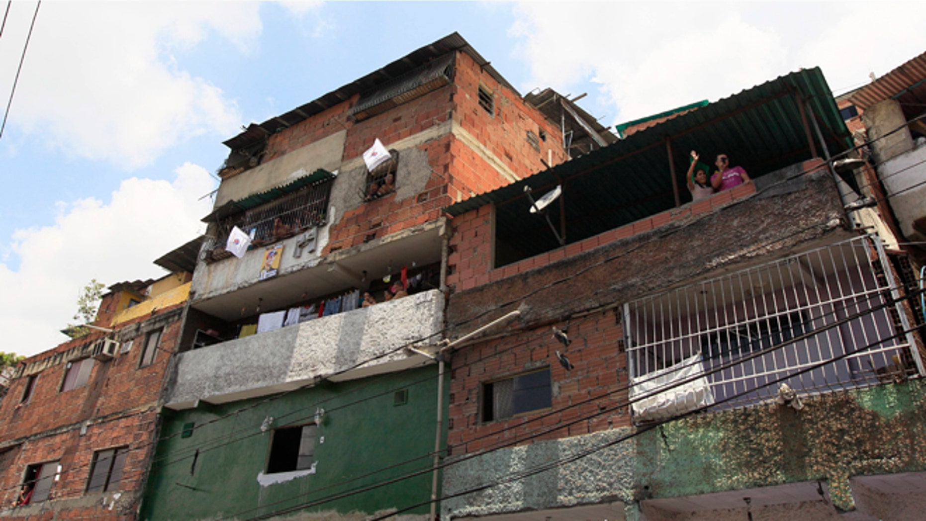 Supporters of opposition presidential candidate Henrique Capriles cheer from the inside of their houses during a campaign rally in Caracas, Venezuela, Sunday, Sept. 16, 2012. Capriles is running against President Hugo Chavez in the country's Oct. 7 election. (AP Photo/Fernando Llano)