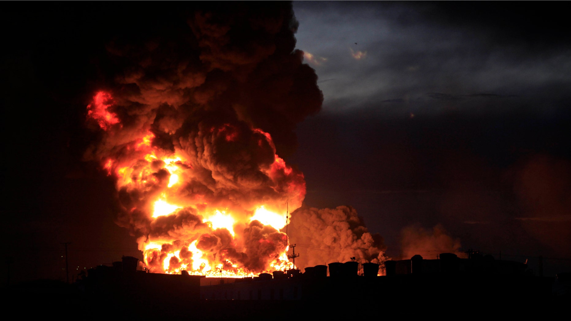 A large fire rises over the Amuay refinery near Punto Fijo, Venezuela, Saturday, Aug. 25, 2012. A huge explosion rocked Venezuela's biggest oil refinery, killing at least 24 people and injuring dozens, an official said. (AP Photo/Ariana Cubillos)