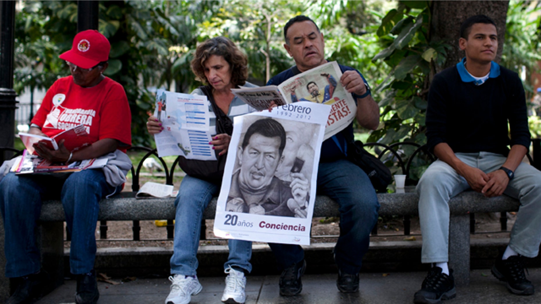 Feb. 28: A man holds a poster of Venezuelas President Hugo Chavez as he reads a paper in Bolivar Square in Caracas.