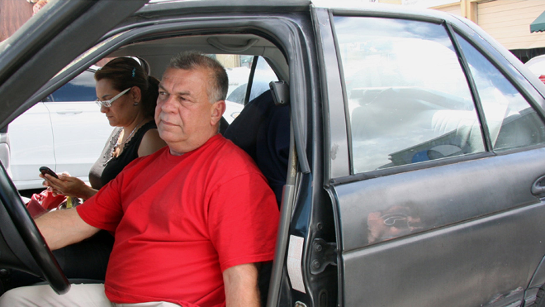 In this Wednesday, March 5, 2014, Carlos Salamanca tries to start his car in Miami. Salamanca fled Venezuela's increasingly political turmoil with his family in January. He is now living largely out of an old Nissan he purchased for $1,000. Salamanca was a small business owner in Venezuela and said he fled after receiving threats against his family. (AP Photo/Christine Armario)