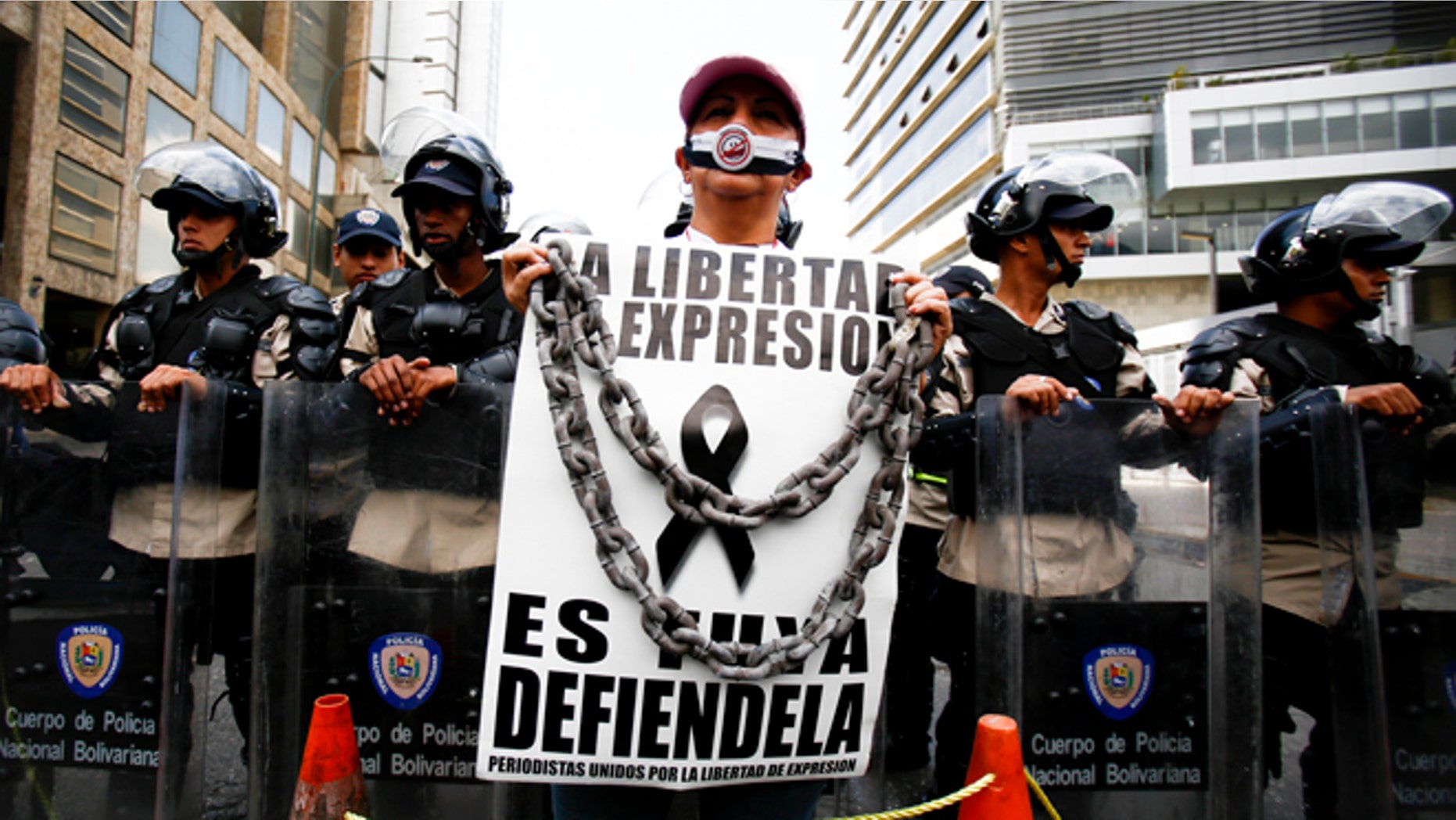 Feb. 11, 2014: A woman with her mouth covered stands before a line of National Bolivarian Police preventing protesters from reaching the national intelligence agency in Caracas, Venezuela.