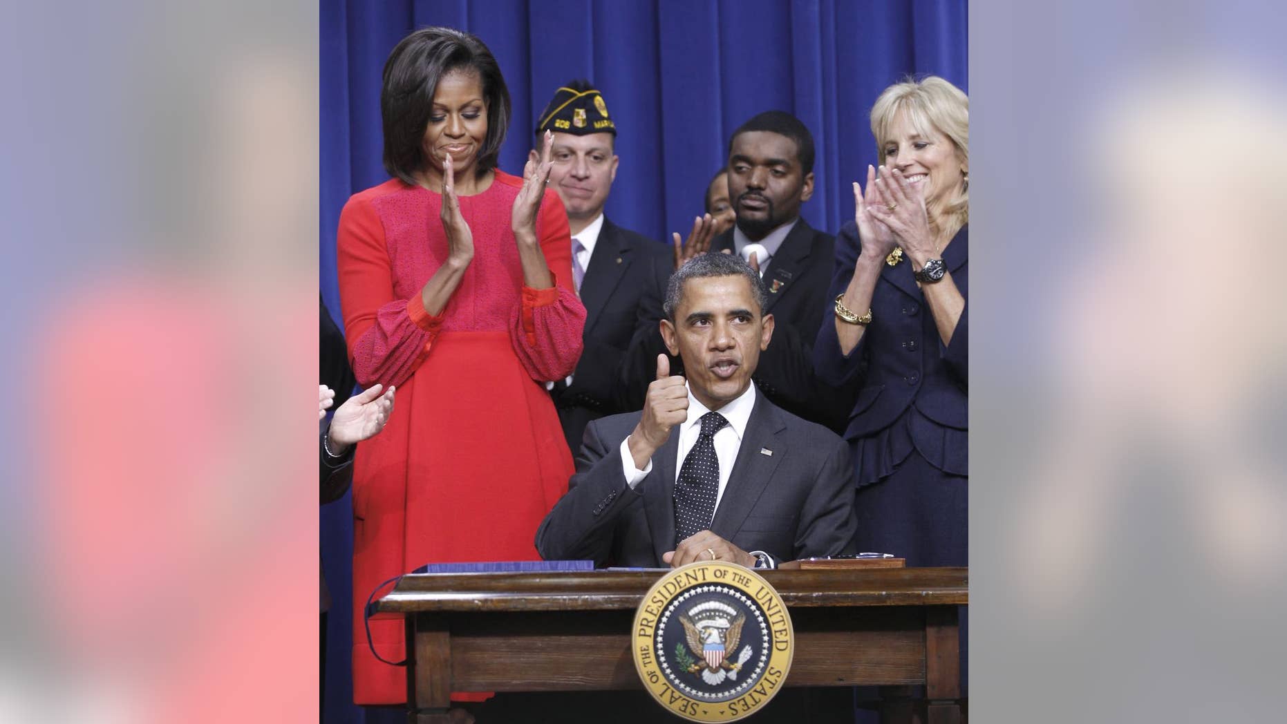President Barack Obama give a 'thumbs-up' after signing legislation that will provide tax credits to help put veterans back to work, Monday, Nov. 21, 2011, during a ceremony at the Eisenhower Executive Office Building on the White House complex in Washington. The president is joined by first lady Michelle Obama, and Dr. Jill Biden. (AP Photo/Pablo Martinez Monsivais)