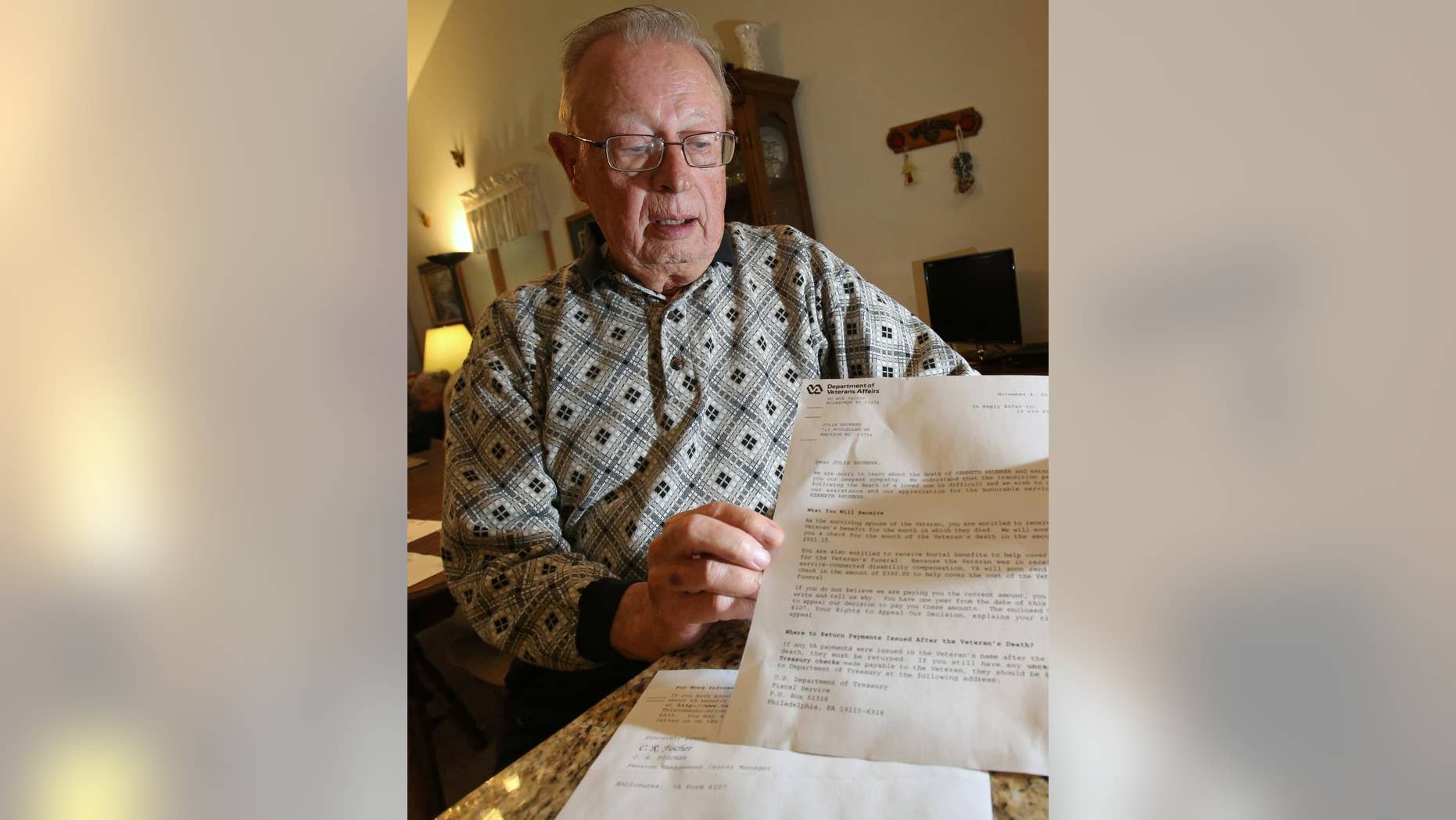In this photo taken on Tuesday, Nov. 11, 2014, Kenneth C. Brunner, holds up a letter at his home in Madison, Wis., that was addressed to his wife from the Department of Veterans Affairs stating that he had died and she would receive a check for the month that he passed. Brunner, an 81-year-old Army veteran, says he tried to call the agency Tuesday to deliver a few choice words, but the office was closed for Veterans Day. (AP Photo/Wisconsin State Journal, Amber Arnold)
