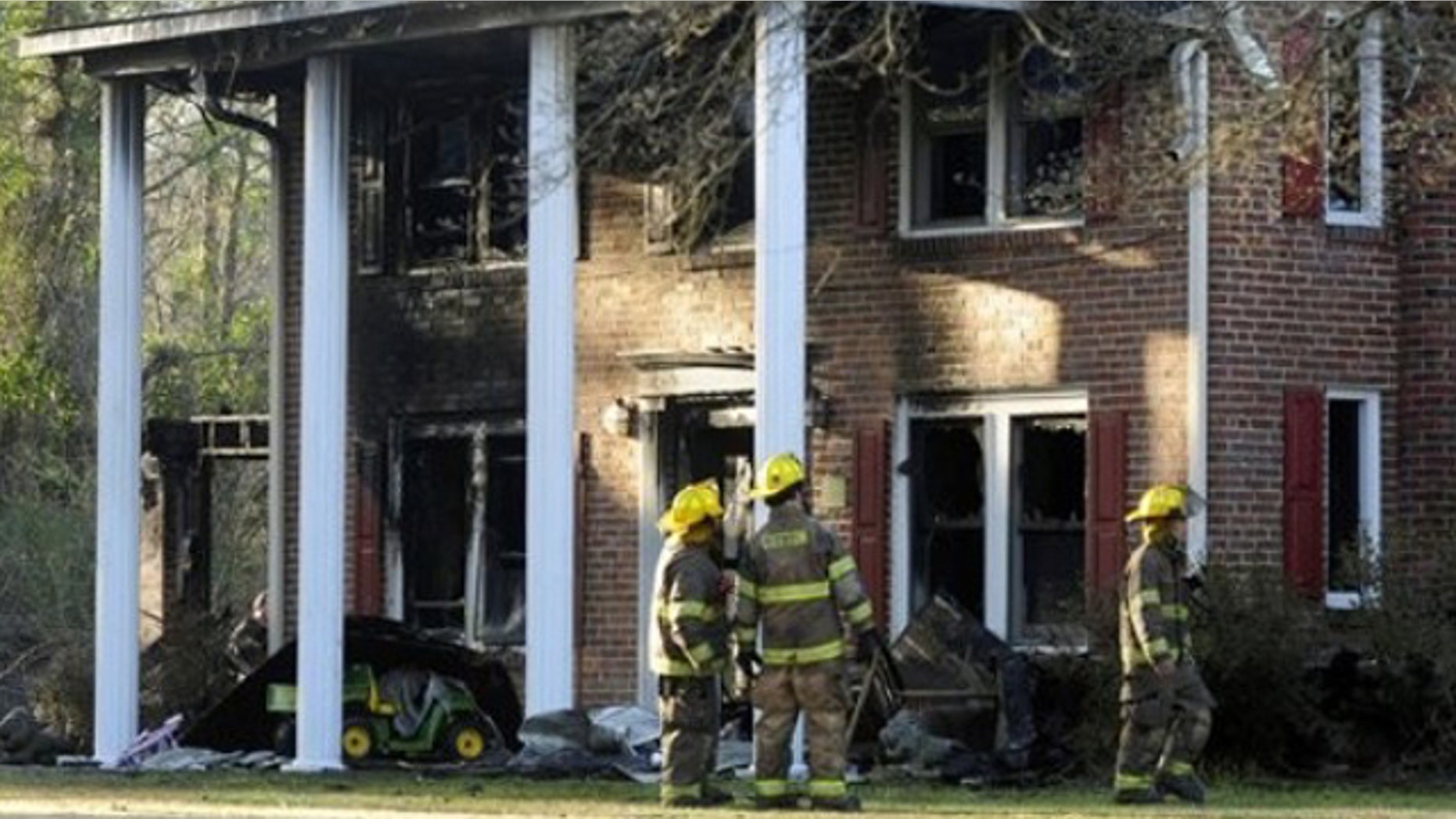 Mar. 6, 2012: Firefighters look at the front of a heavily damaged two- story home where a Special Forces soldier died trying to rescue his 2 small children during a house fire.