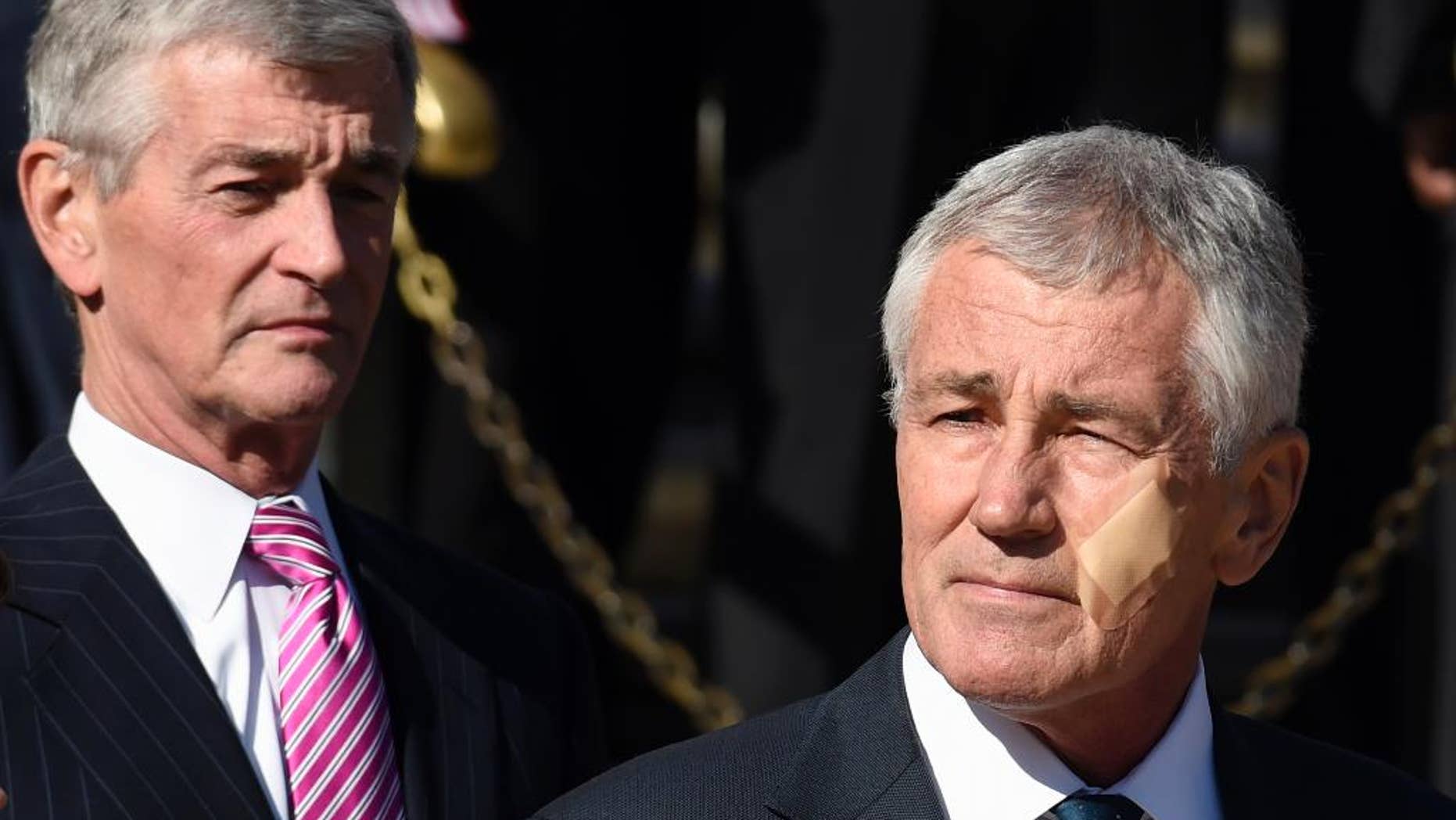 Defense Secretary Chuck Hagel, right, and Army Secretary John McHugh attend a wreath laying ceremony at the Tomb of the Unknowns, Tuesday, Nov. 11, 2014, at Arlington National Cemetery in Arlington, Va. in honor of Veterans Day. Hagel sports a bandage on his cheek after a minor kitchen mishap needing no stitches. (AP Photo/Susan Walsh)