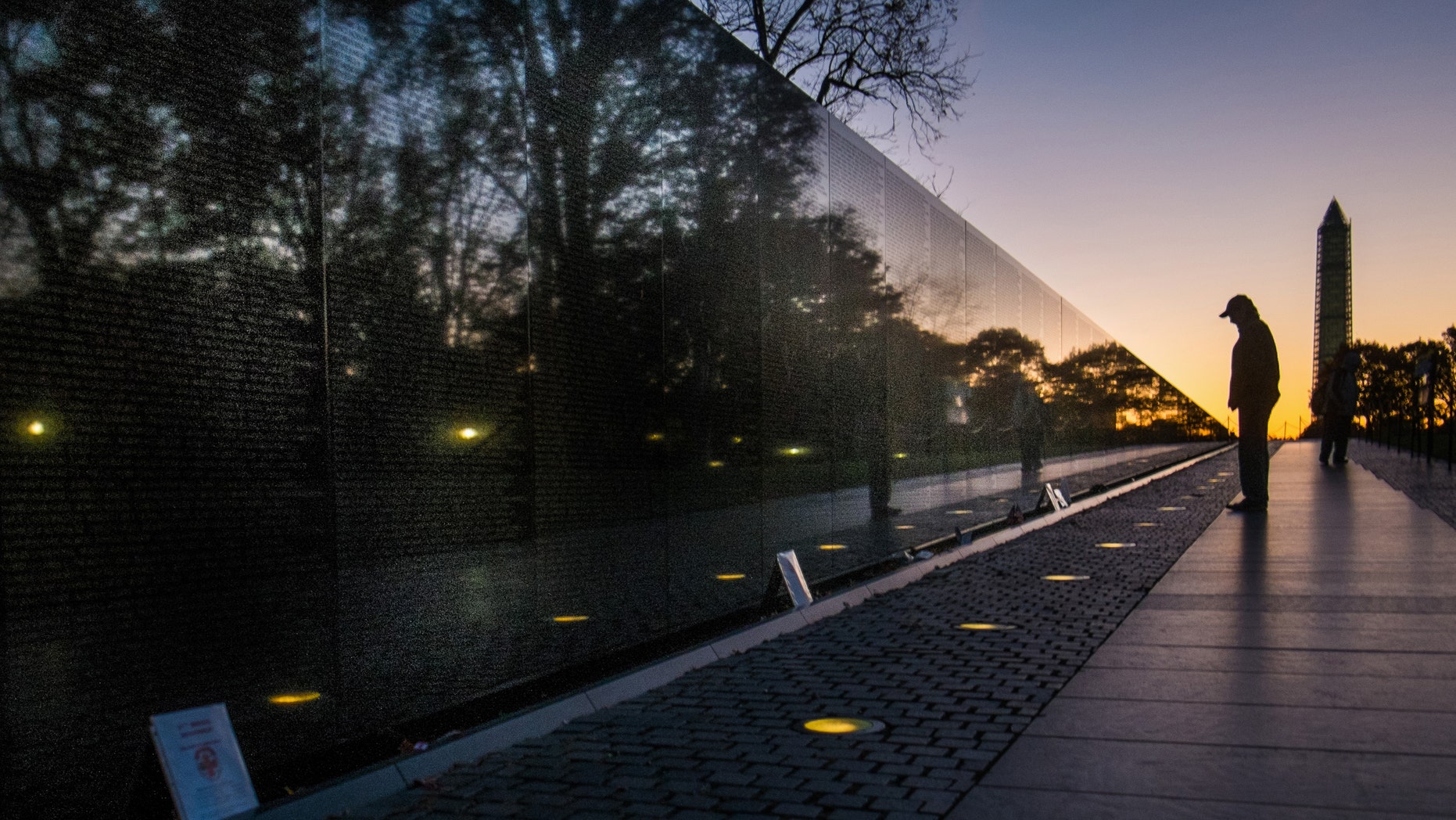 A visitor at the Vietnam War Memorial in Washington passes early in the morning on Veterans Day, Monday, to look at the names inscribed on the wall.