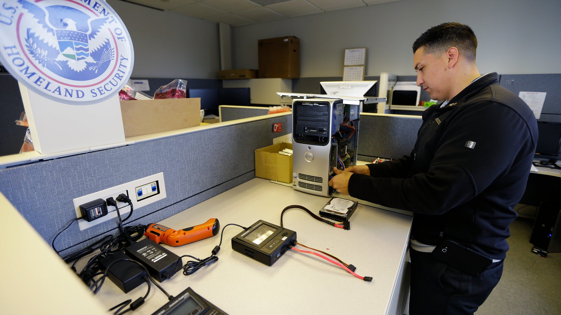 Army Staff Sgt. Oskar Zepeda removes a hard drive from a computer seized as evidence, Monday, Dec. 16, 2013, at a Digital Forensics Lab at an Immigration and Customs Enforcement field office in Seattle, where he is serving a one-year internship. Zepeda, who served nine tours of duty in Iraq and Afghanistan, before being wounded, is part of a 17-member class of veterans deployed to ICE field offices throughout the country to use his newly acquired skills in computer forensics to help capture and prosecute child predators. (AP Photo/Ted S. Warren)