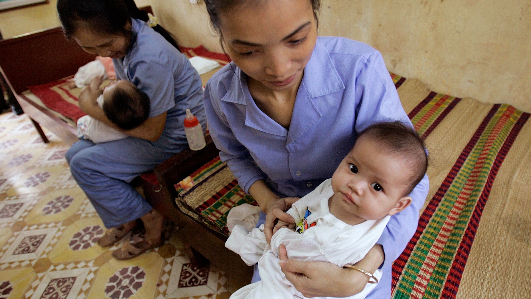 April 23, 2008 FILE photo of 5-month-old baby girls cradled by workers at an orphanage in Bac Ninh province, near Hanoi, Vietnam. Vietnam and the US will soon resume limited inter-country adoptions, 6 years after an imposed ban because of allegations of widespread baby-selling and children offered without the consent of birth parents.