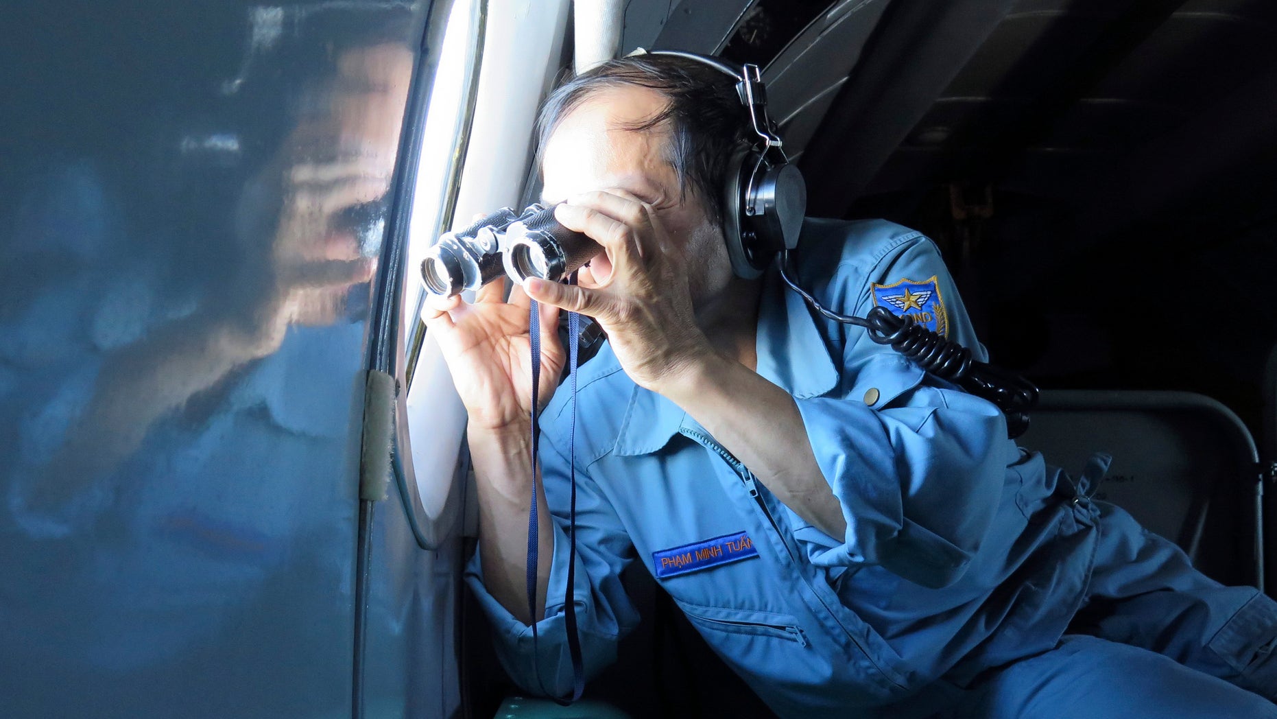 Vietnamese Air Force Col. Pham Minh Tuan uses binoculars on board a flying aircraft during a mission to search for the missing Malaysia Airlines flight MH370 in the Gulf of Thailand over the location where Chinese satellite images showed possible debris from the missing Malaysian jetliner, Thursday, March 13, 2014. (AP Photo)