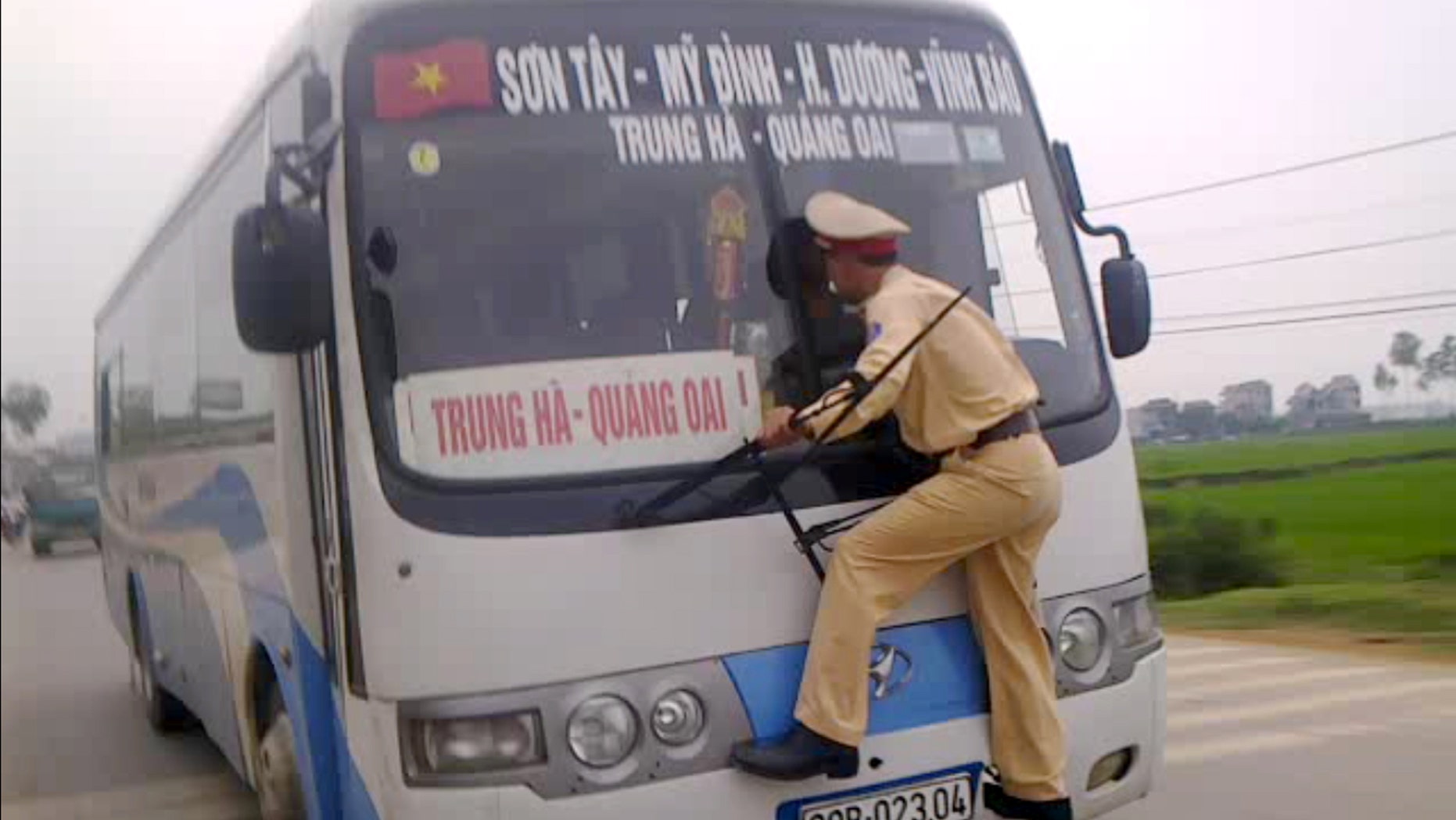 April 9, 2012: In this photo made from a video filmed and released by Hanoi Police, Vietnamese traffic police 2nd Lt. Nguyen Manh Phan clings on to the windshield wipers of a moving bus as he goes on a wild ride for nearly a 0.62 miles after the rogue driver tried to avoid a ticket in Ba Vi District outside Hanoi, Vietnam.