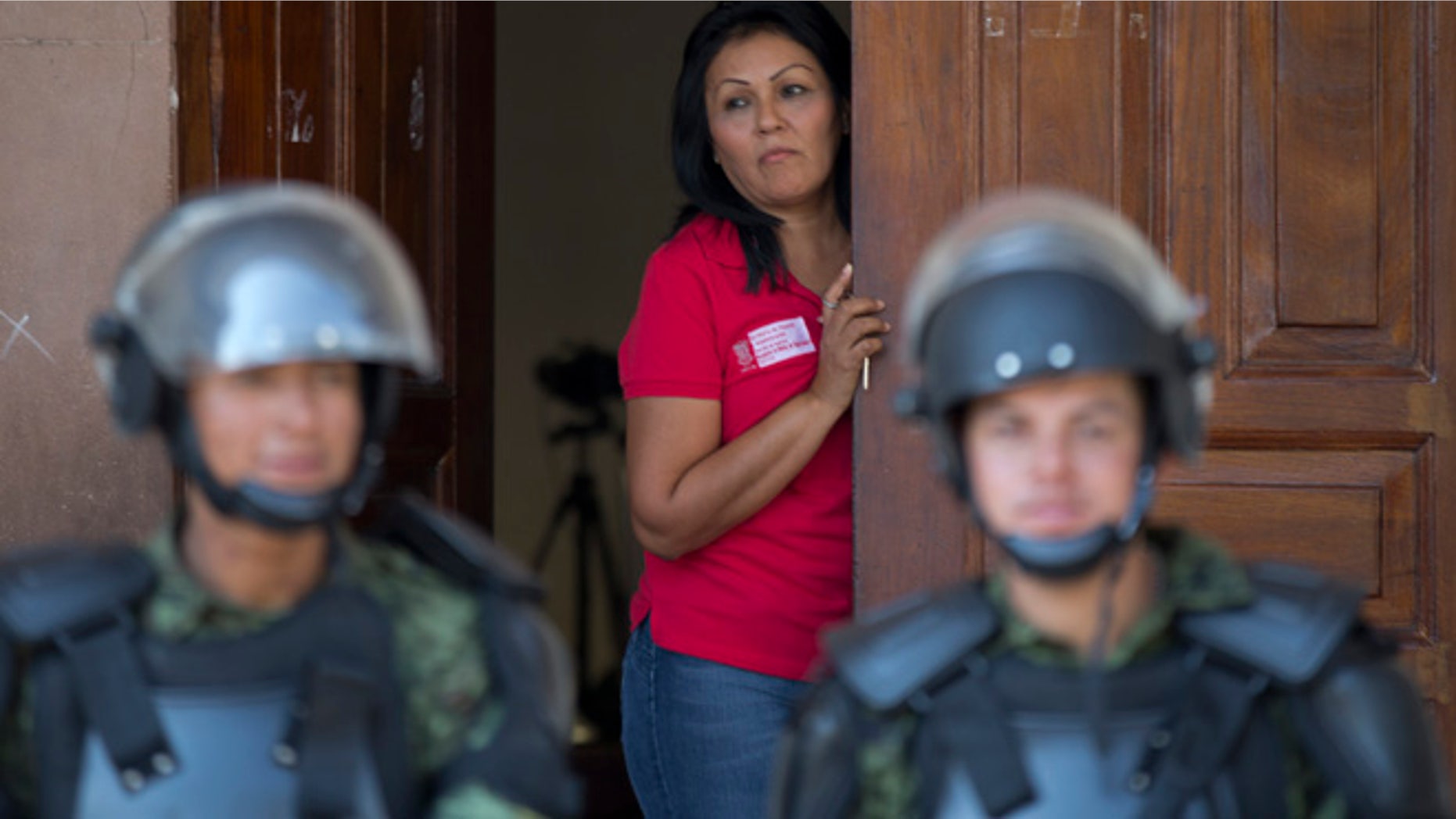 Jan. 14: A city employee looks out from a City Hall Hall doorway as a cordon of soldiers guard the government building in Apatzingan, Mexico. Mexican soldiers and federal police kept a tense standoff with vigilantes Tuesday after a new government campaign to stop violence in the western Michoacan state turned deadly.