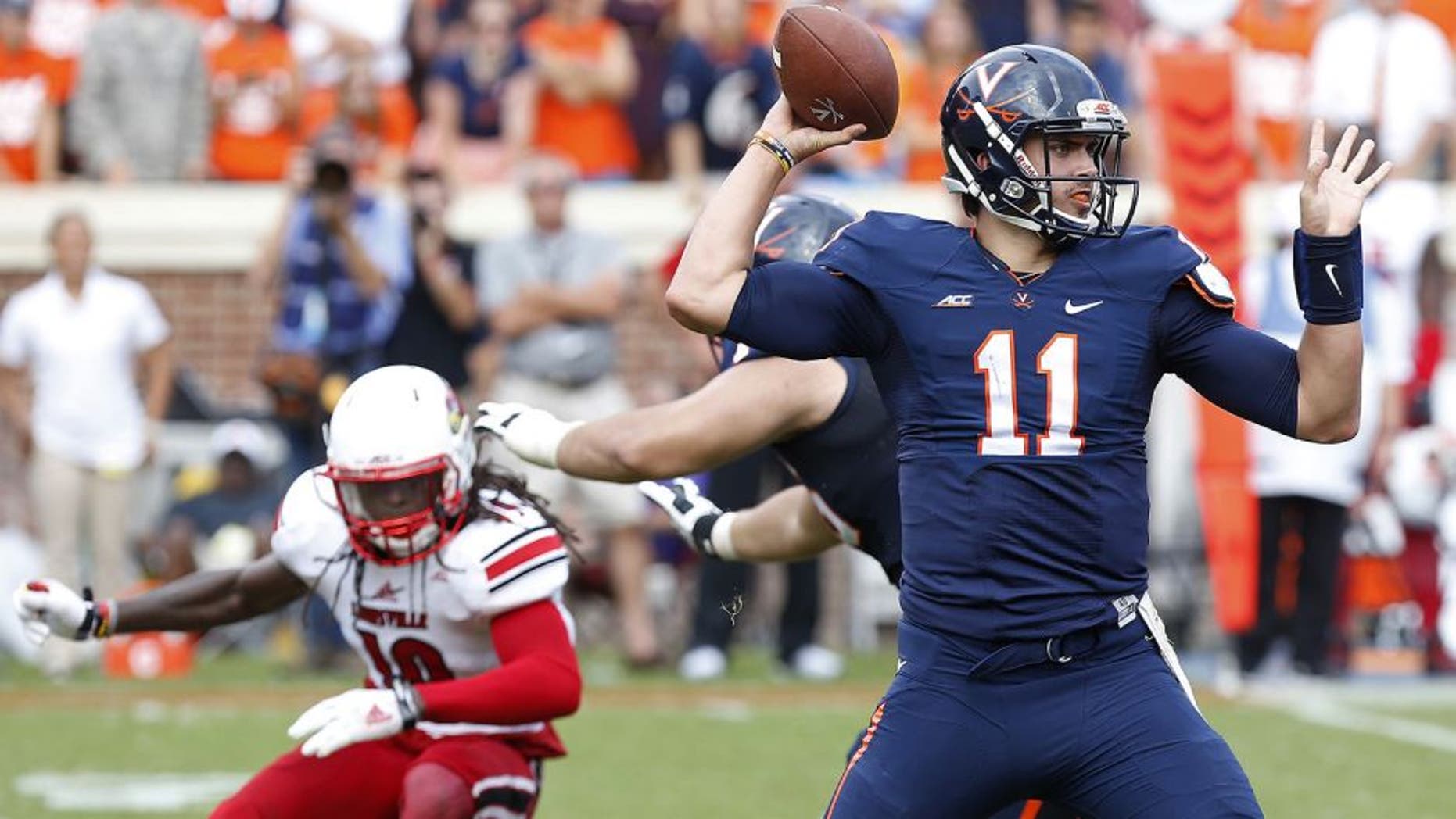Sep 13, 2014; Charlottesville, VA, USA; Virginia Cavaliers quarterback Greyson Lambert (11) throws the ball as Louisville Cardinals cornerback Terell Floyd (19) chases in the fourth quarter at Scott Stadium. The Cavaliers won 23-21. Mandatory Credit: Geoff Burke-USA TODAY Sports
