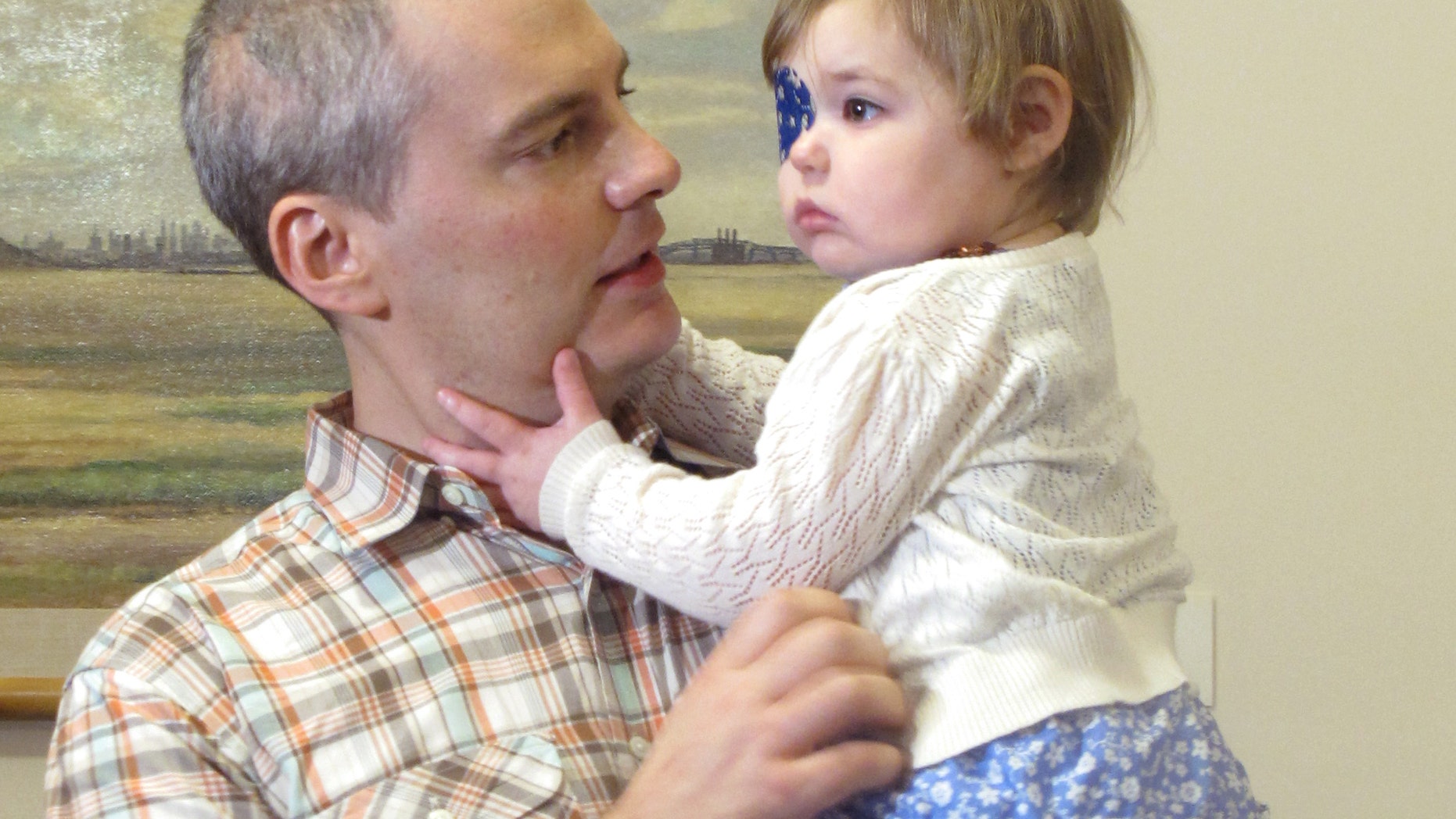 Brian Wilson, of Scotch Plains, N.J. holds his 2-year-old daughter Vivian as they prepare to deliver boxes of letters to Gov. Chris Christie's office in Trenton, N.J., on Thursday, Aug. 1, 2013. (AP Photo/Geoff Mulvihill)