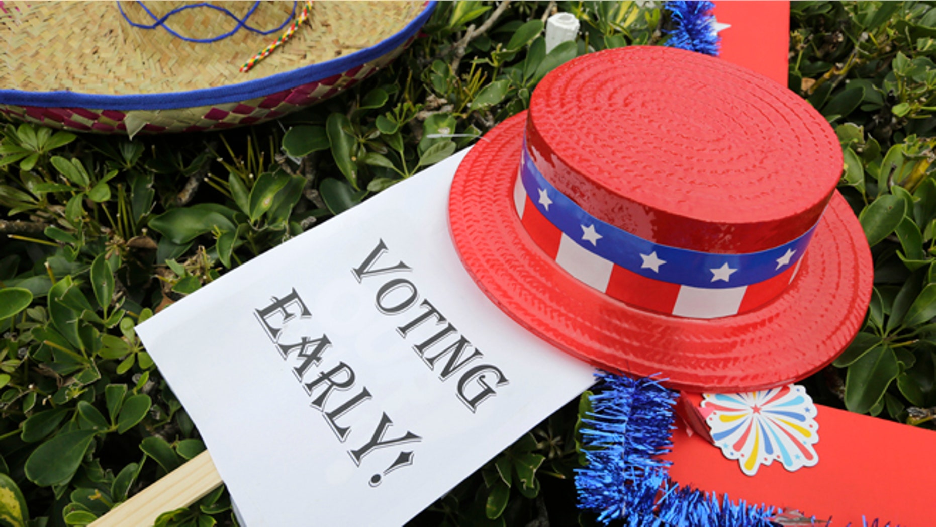 In this Oct. 24, 2016, photo, an early voting sign is placed on the grass at an early voting celebration outside of Jackson Memorial Hospital, on the first day of early voting in Miami. The millions of votes that have been cast already in the U.S. presidential election point to an advantage for Hillary Clinton in critical battleground states, as well as signs of strength in traditionally Republican territory. (AP Photo/Lynne Sladky)