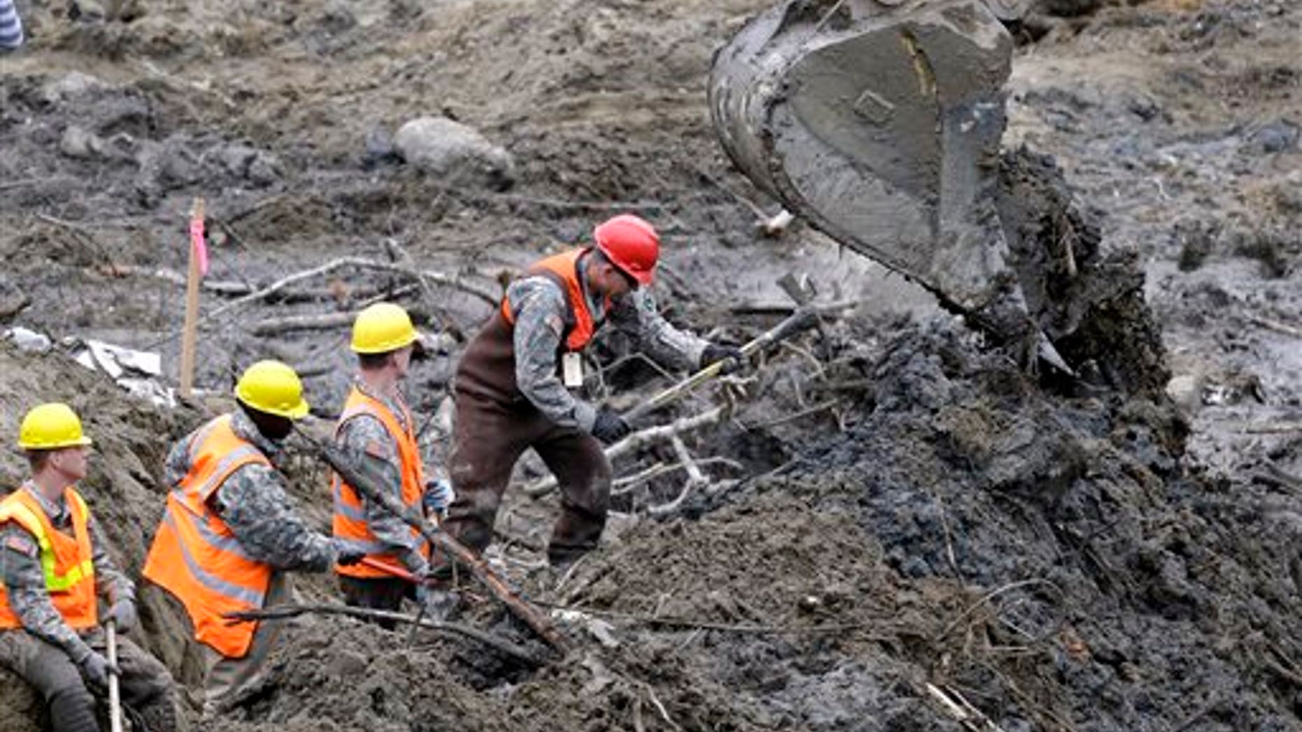 Workers use hand tools next to heavy equipment at the scene of a deadly mudslide in Oso, Wash., earlier this month.