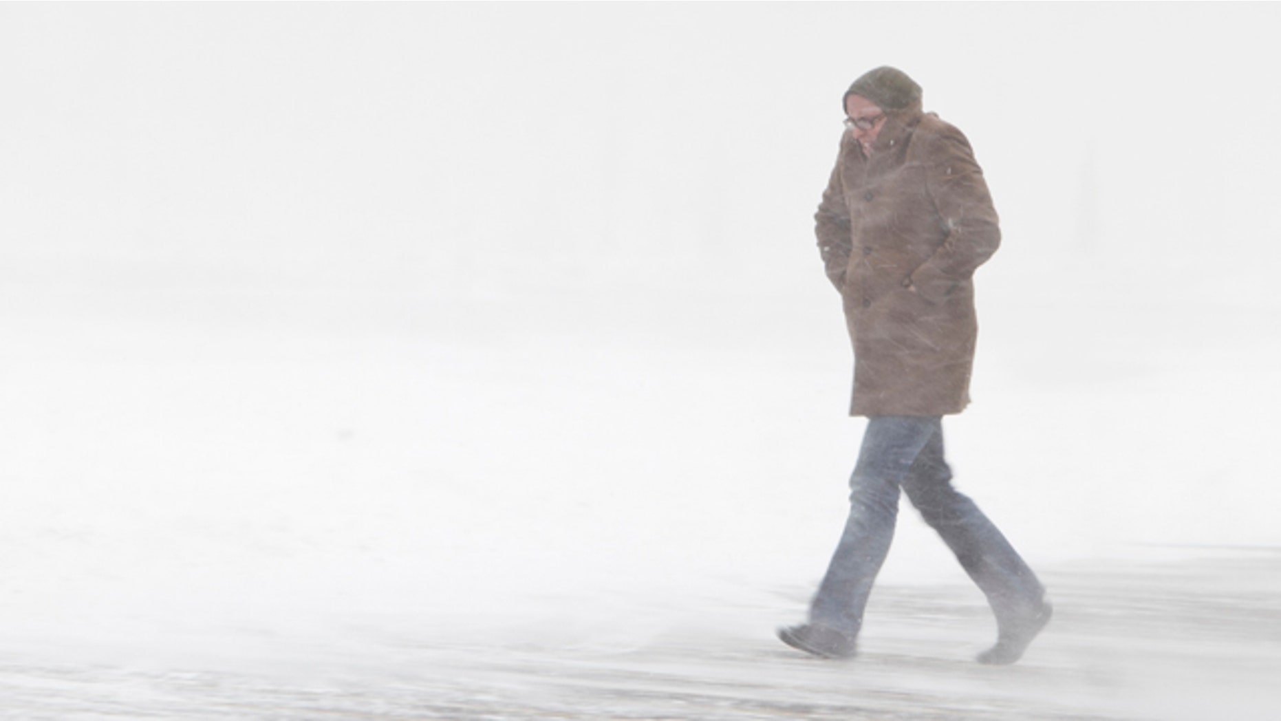 A shopper walks in the parking lot of a store amid blowing snow, in Omaha, Neb.