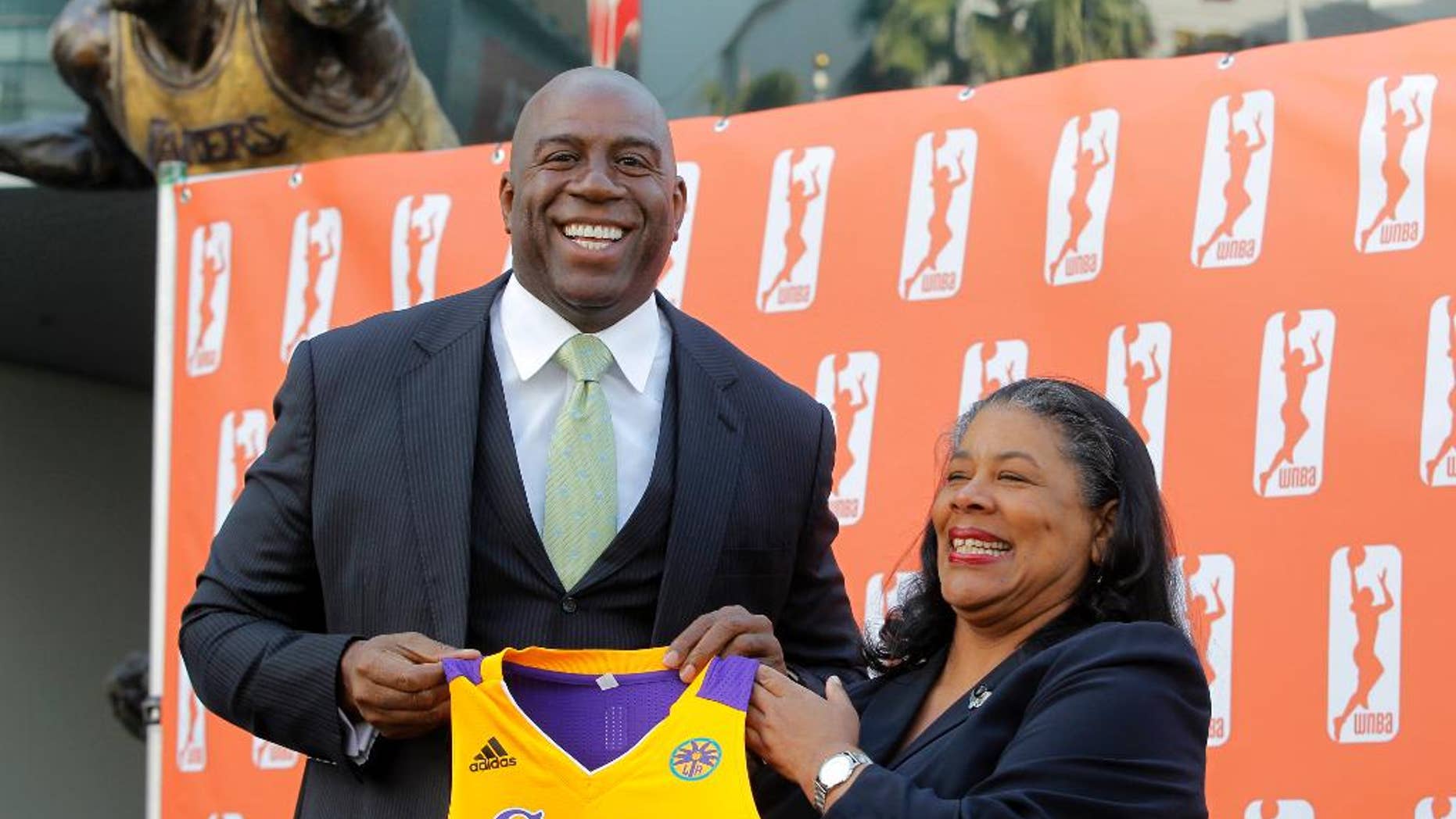 FILE - In this Feb. 5, 2014, file photo, former Los Angeles Laker Magic Johnson is joined by WNBA President Laurel Richie as they pose for photographers after a news conference in front of Staples Center in Los Angeles. Johnson is part of a group buying the Los Angeles Sparks of the WNBA. At upper left is a statue of Johnson. Richie is ready for the games to begin after a turbulent offseason. Richie faced the first major challenges of her presidency, including overseeing negotiations for a new collective bargaining agreement and the sale of the Sparks to a group headed by Johnson. (AP Photo/Nick Ut, File)